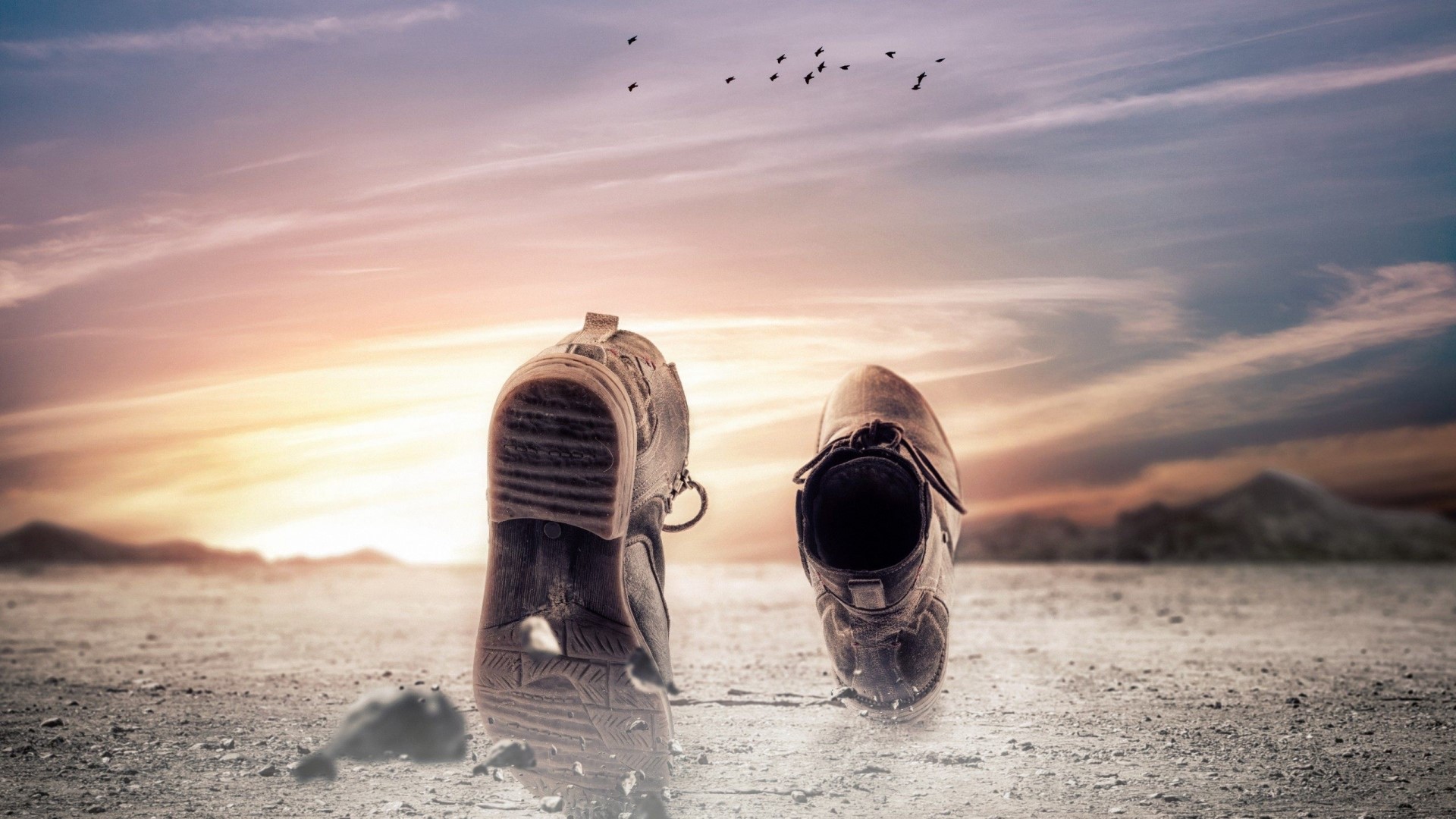 Pair of worn walking shoes on dusty ground at sunset HD Wallpaper
