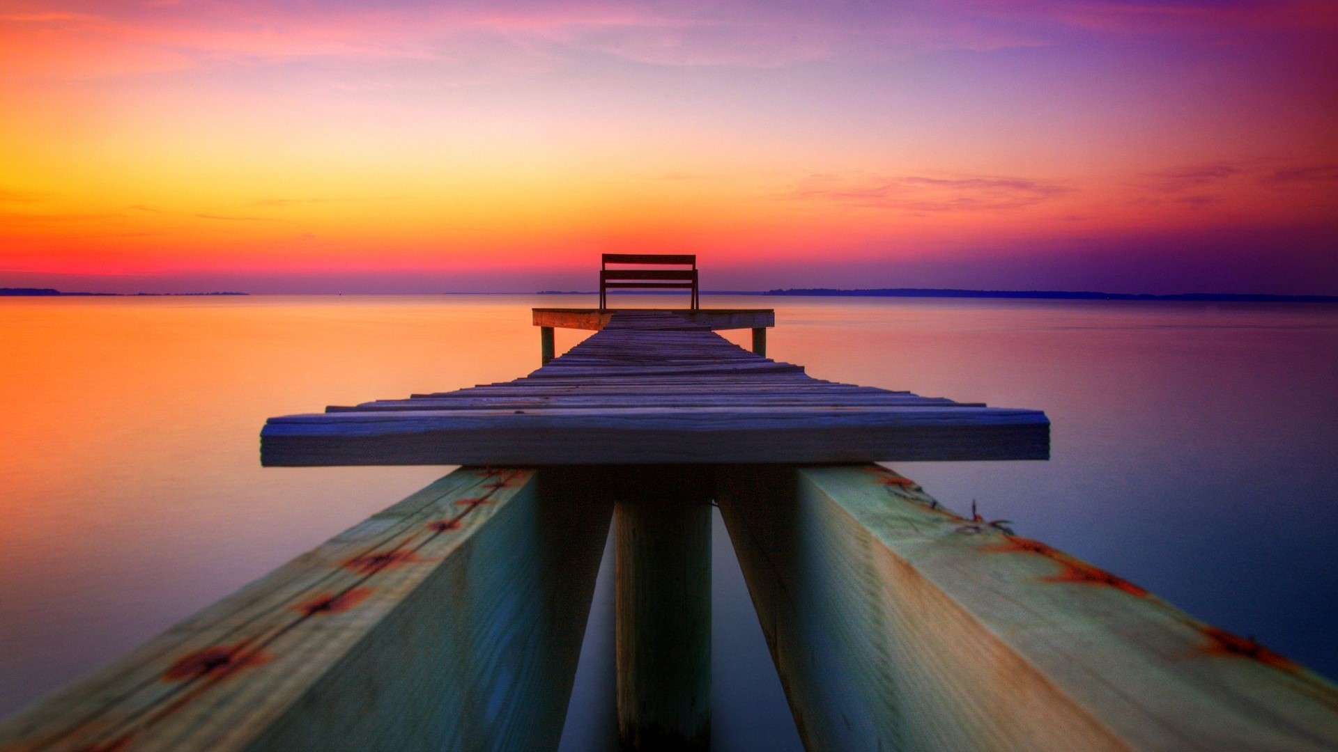 Dock with bench at sunset over water HD Wallpaper