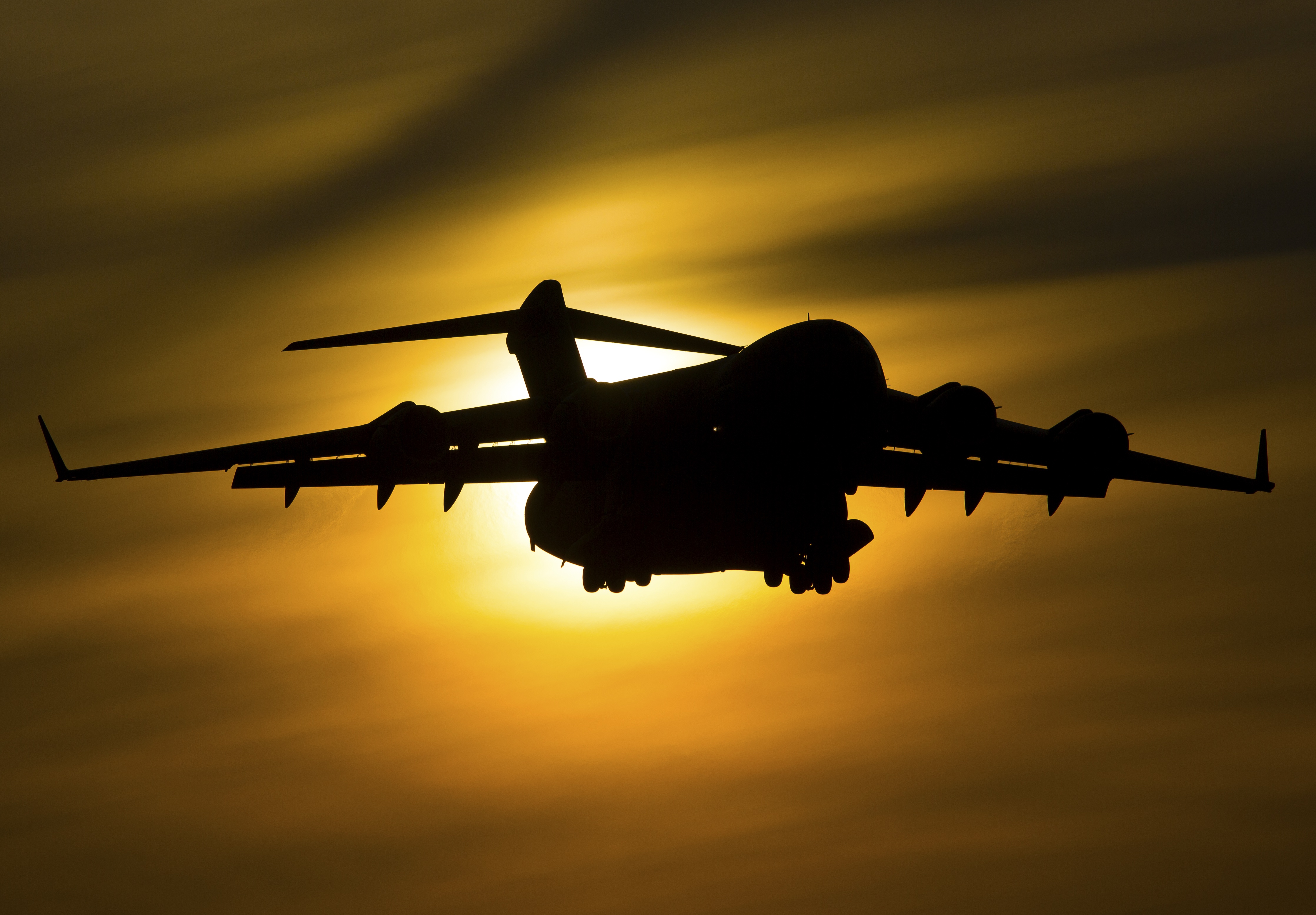 Silhouette of a Boeing C-17 Globemaster III aircraft against the sun HD Wallpaper