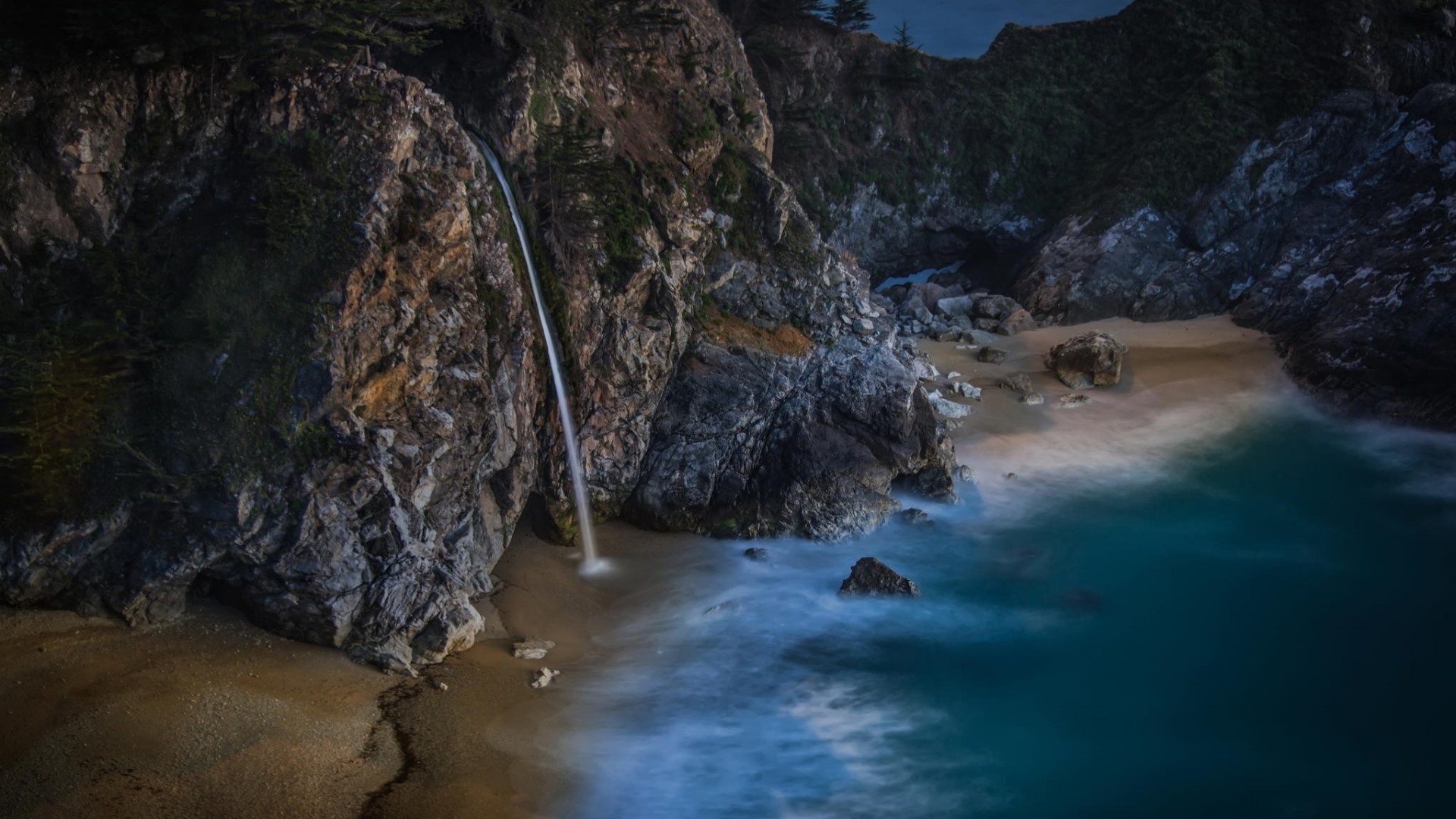 Waterfall on a rocky California beach at dusk HD Wallpaper
