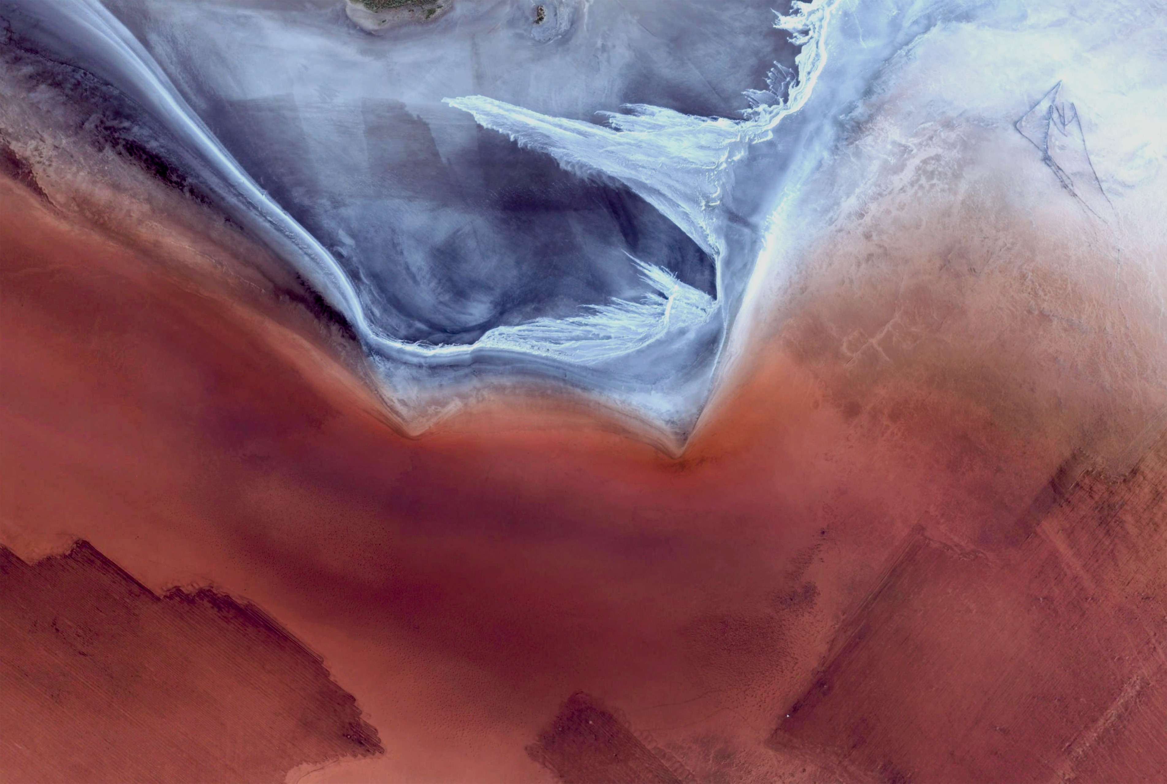 Satellite imagery of a desert landscape with red and blue hues HD Wallpaper