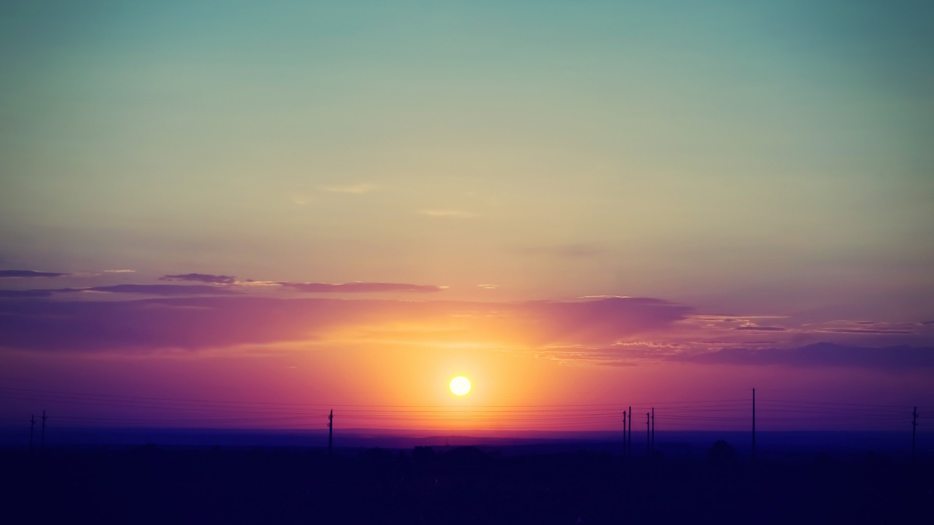 Orange and purple sunset over a dark landscape with power lines HD Wallpaper