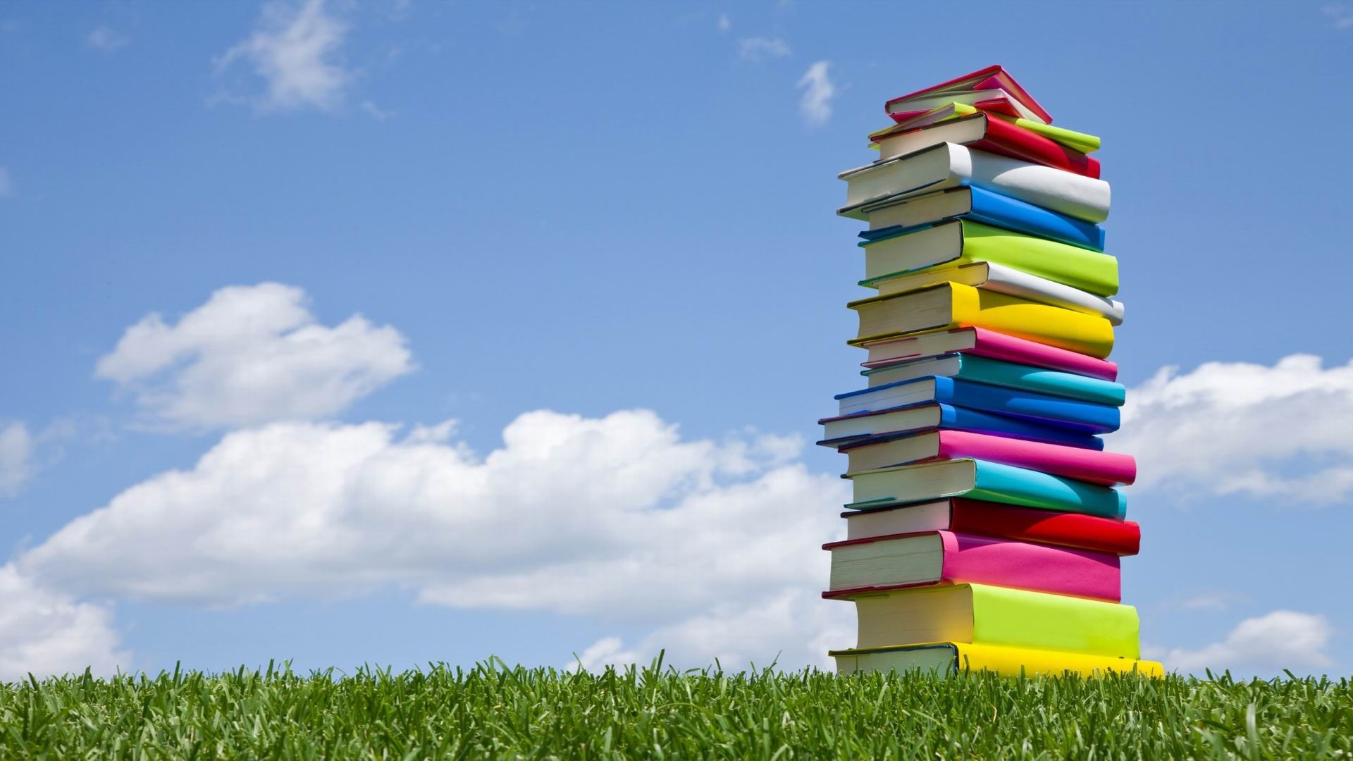 Stack of colorful books against blue sky HD Wallpaper