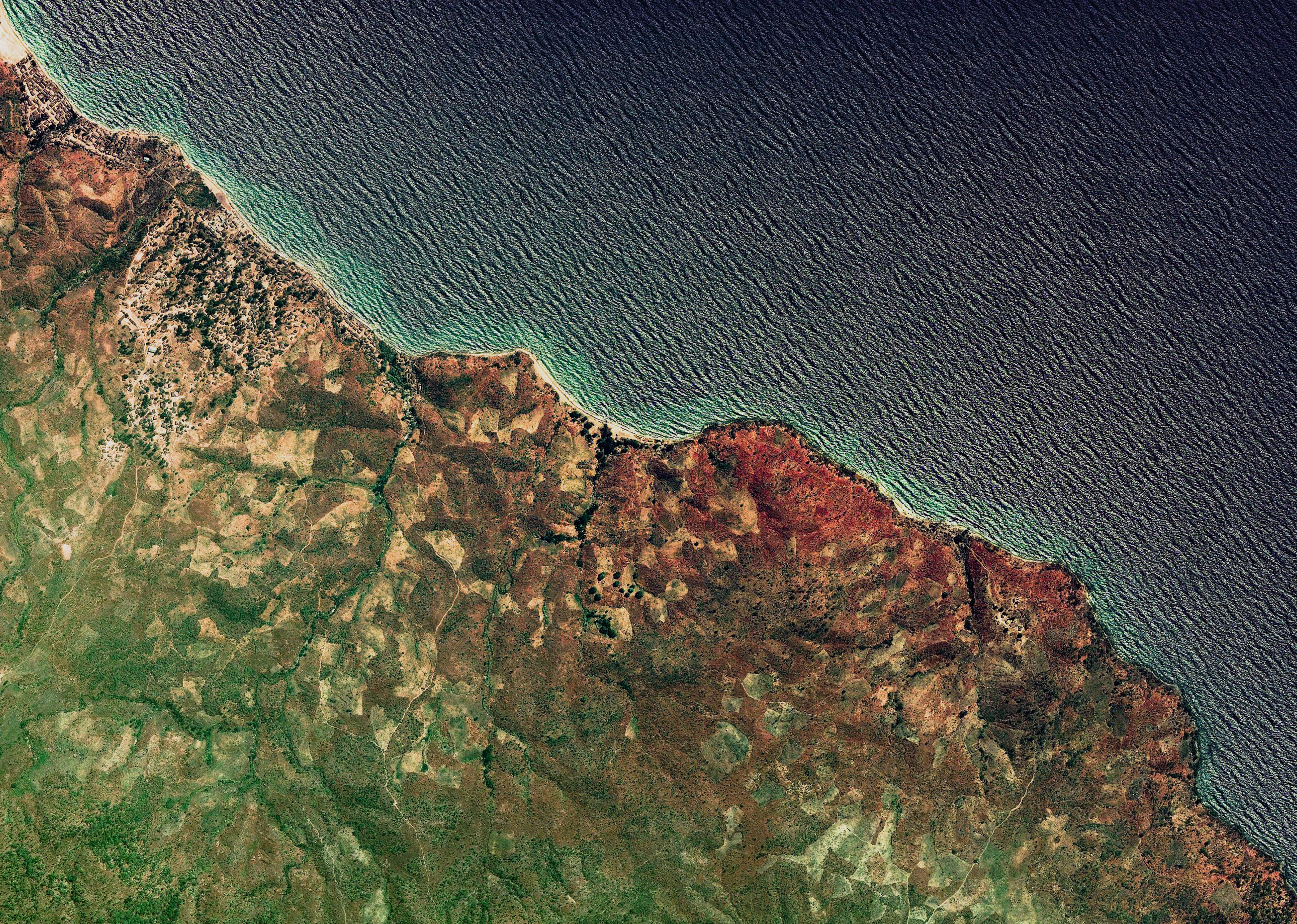 Satellite imagery of a coastline with ocean and land HD Wallpaper
