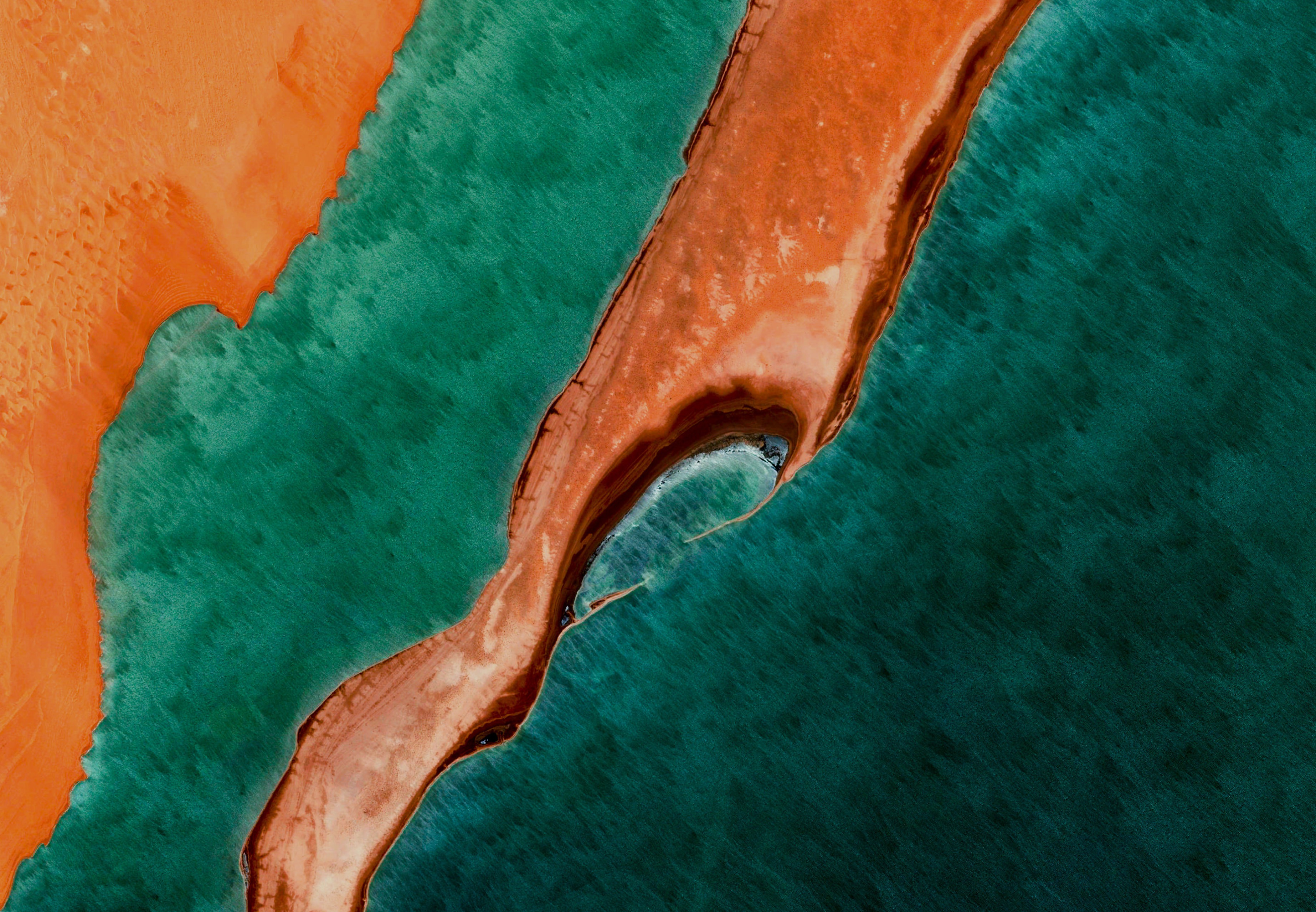 Satellite imagery of a coastline with orange land and teal water 4K HD Wallpaper