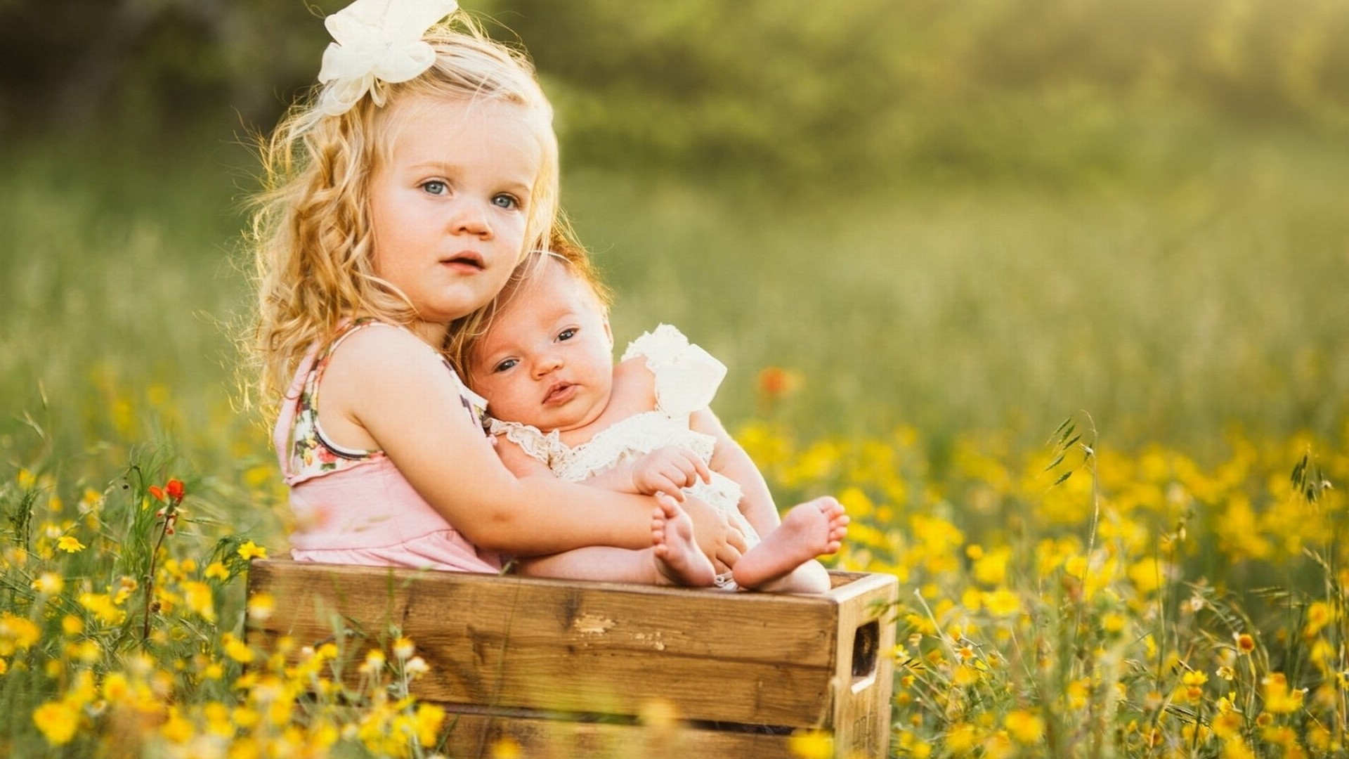 Big Sister Holding Baby in Field of Yellow Flowers HD Wallpaper