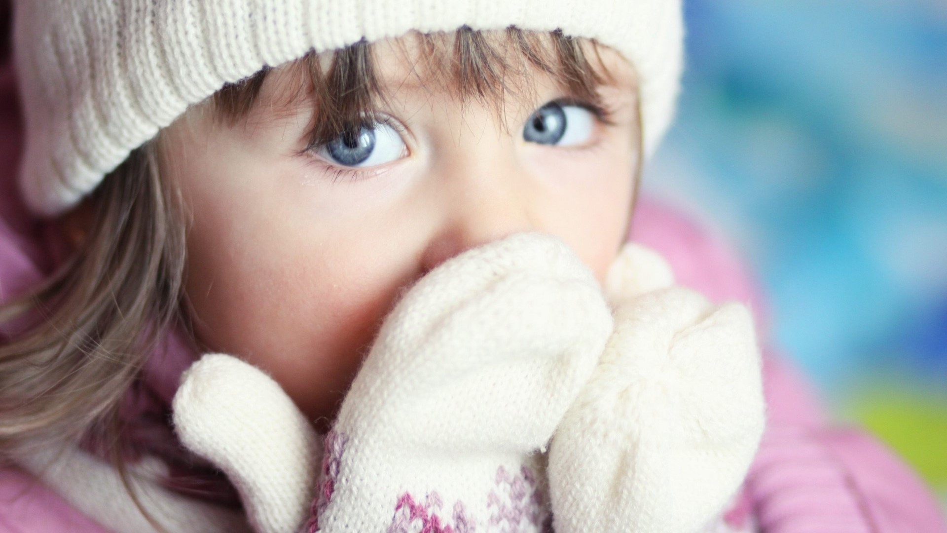 Close-up of a young girl with blue eyes wearing a winter hat and mittens HD Wallpaper