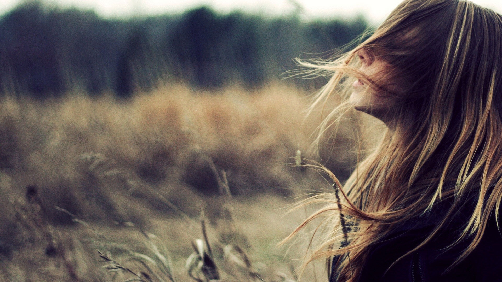 Blonde girl with hair blowing in the wind in a field HD Wallpaper