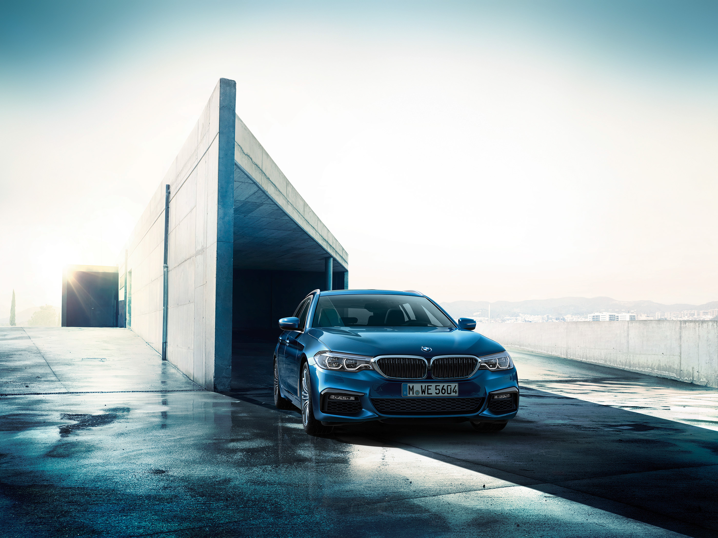Blue BMW 5 Series Touring G31 parked outside modern building HD Wallpaper