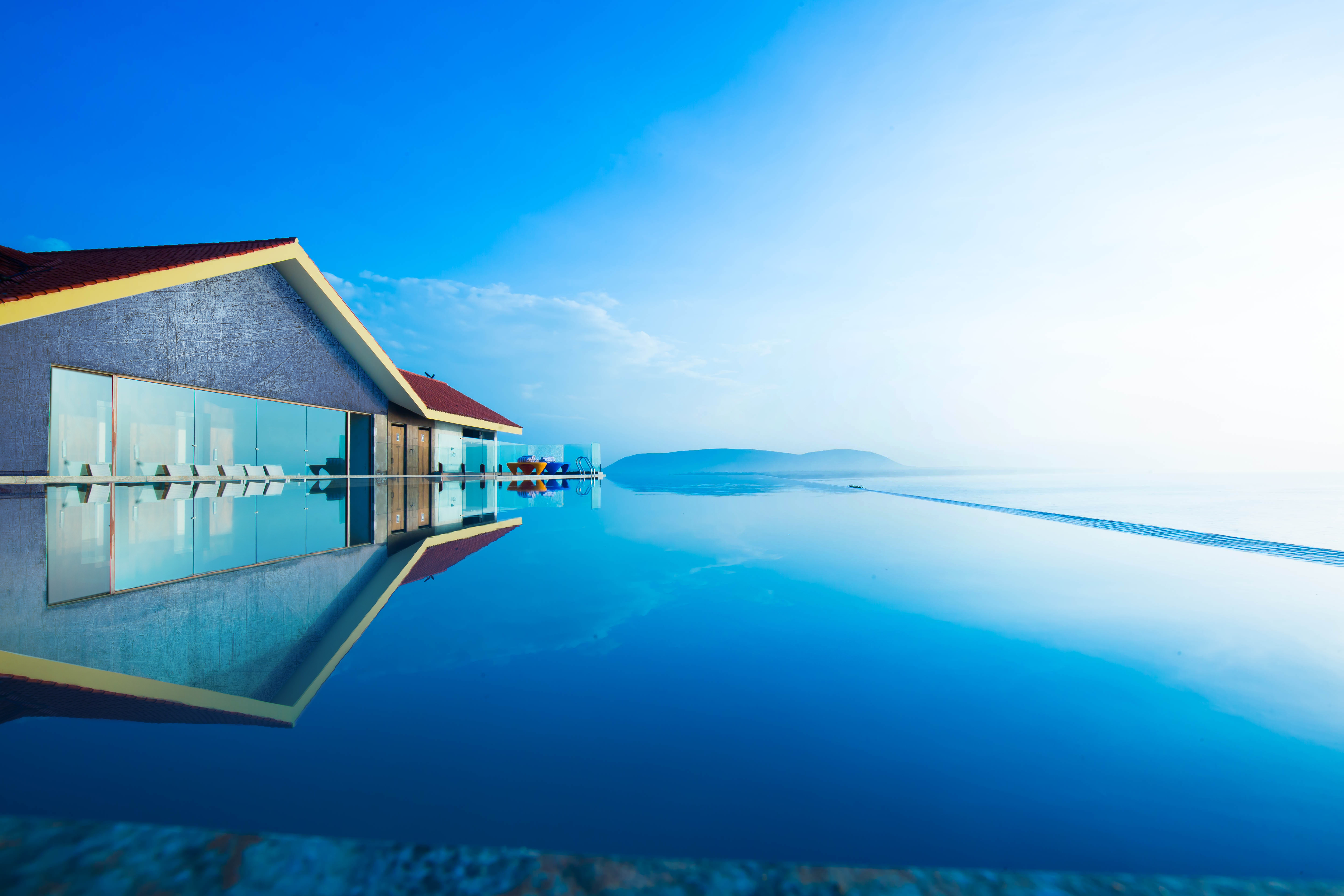 Infinity pool at a beach resort with a modern building HD Wallpaper