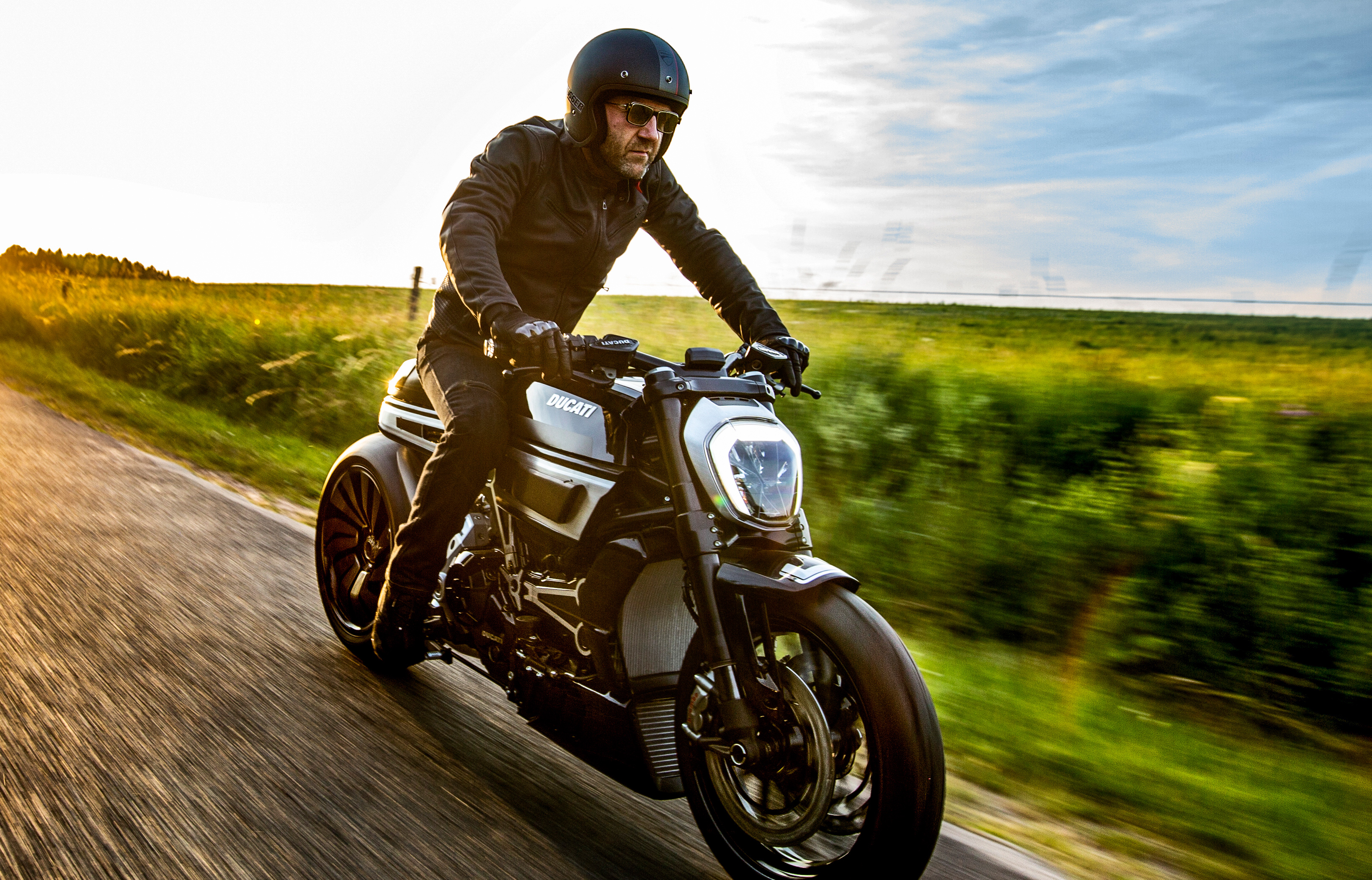Man riding a Ducati XDiavel motorcycle on a road HD Wallpaper