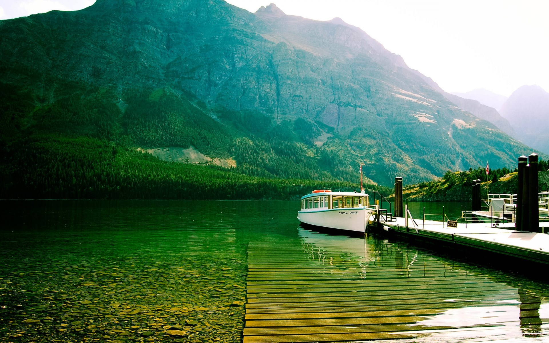 Boat docked on a lake with mountains in the background HD Wallpaper
