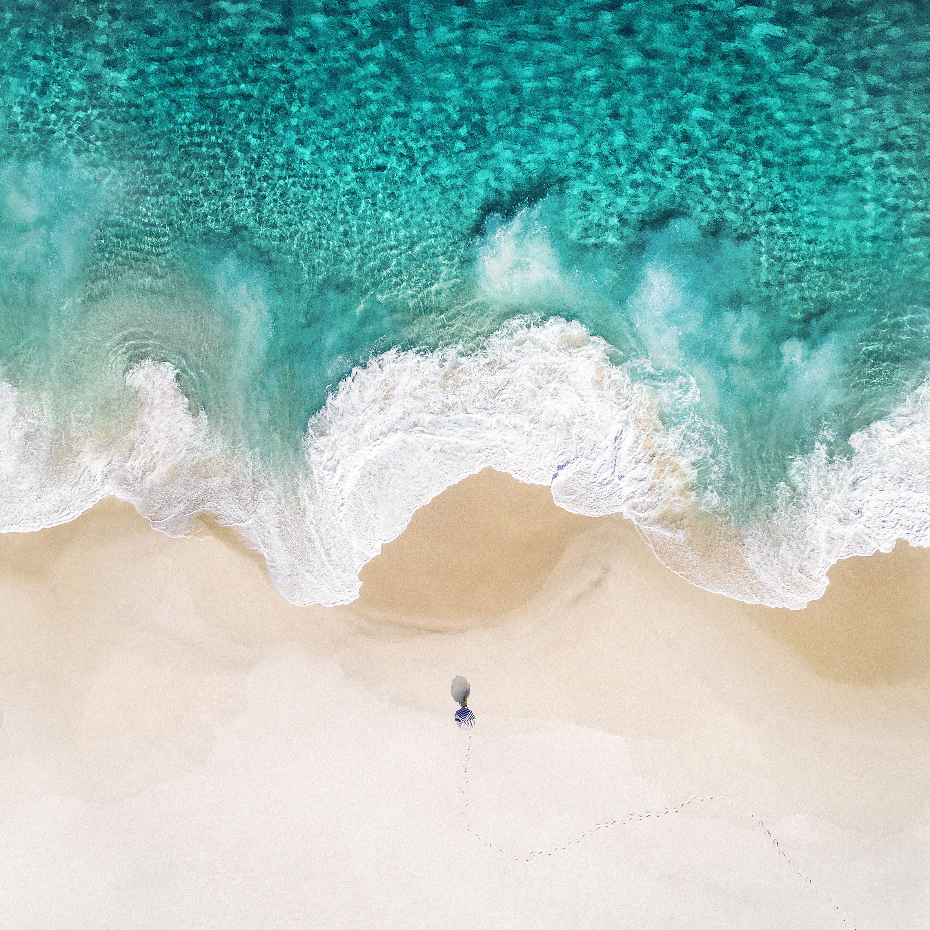 Person walking on a sandy beach with ocean waves HD Wallpaper