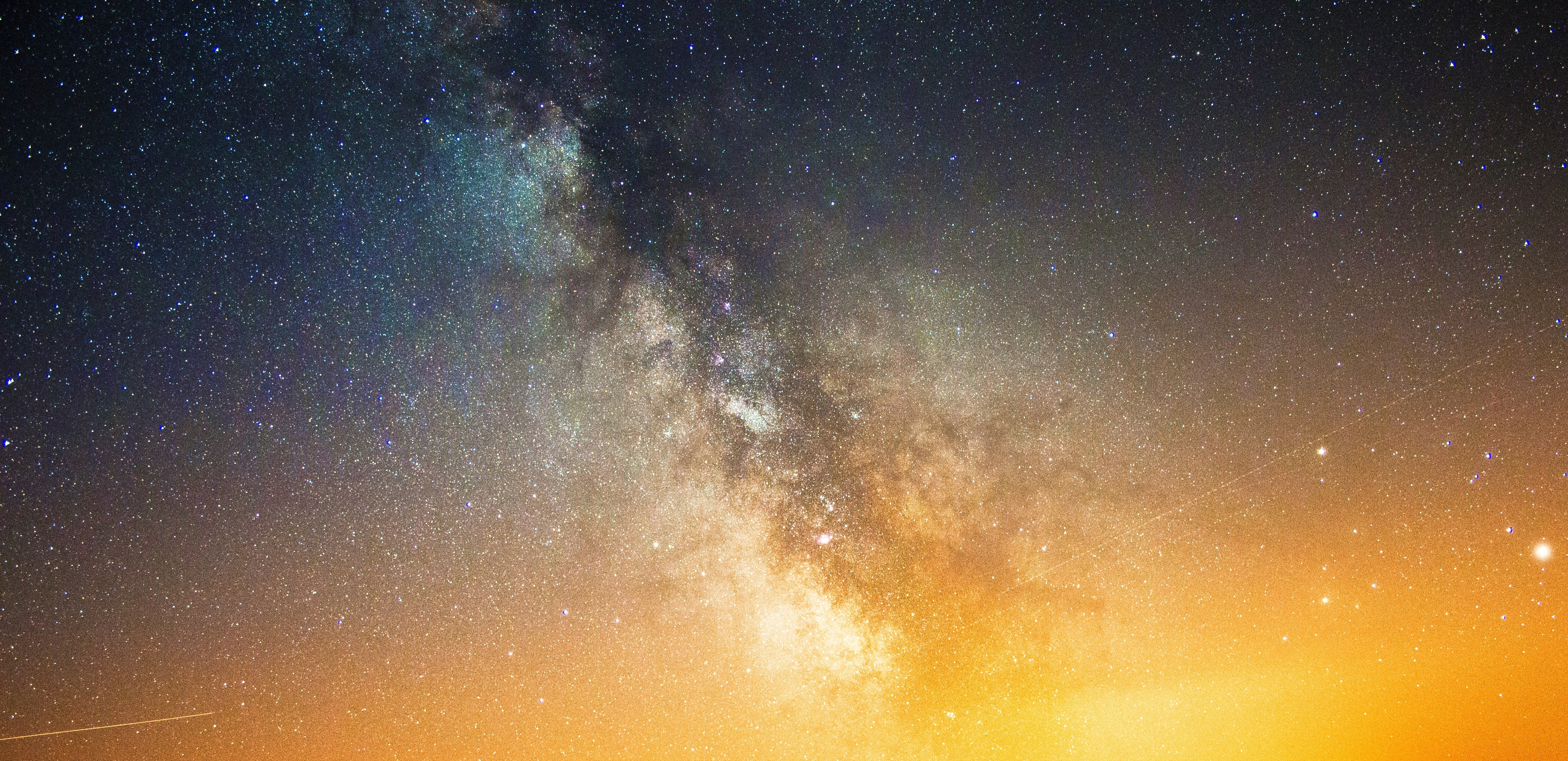 Milky Way galaxy with stars and orange glow HD Wallpaper