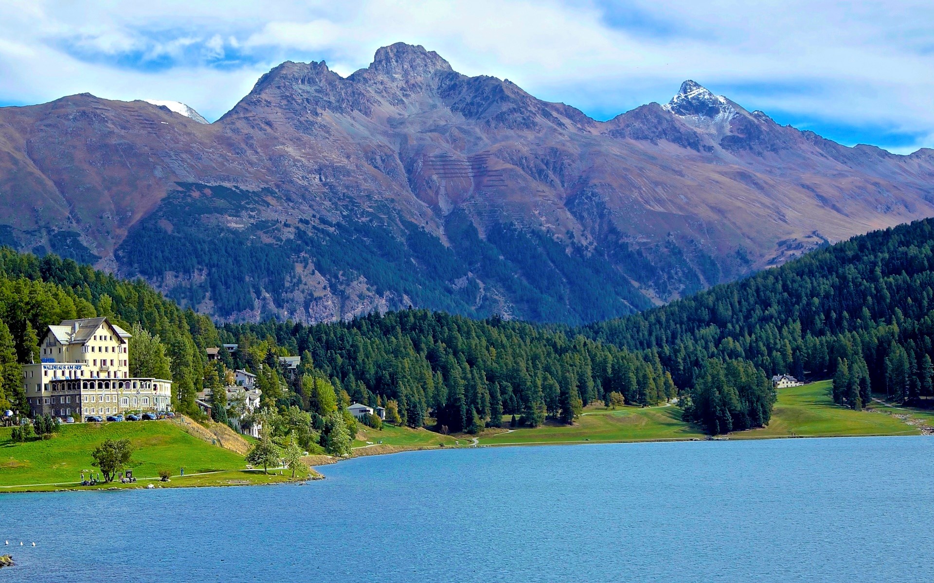 Hotel building on a lake with mountains and forest HD Wallpaper