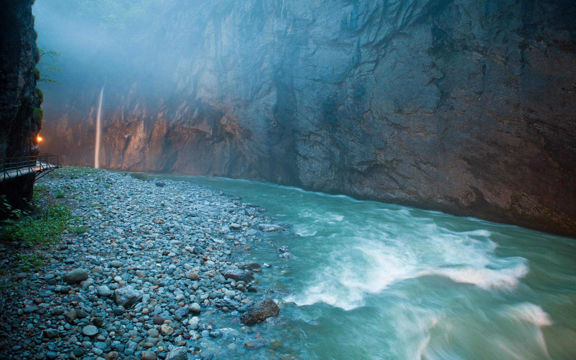 River flowing through a misty gorge with a waterfall HD Wallpaper