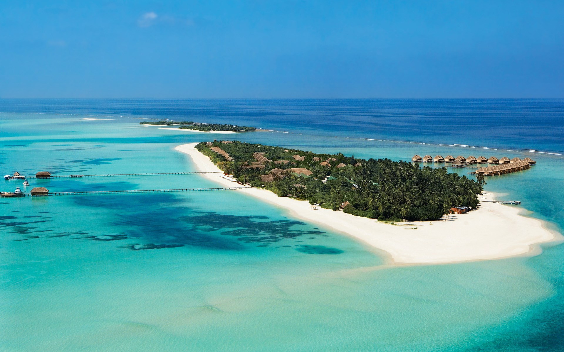 Aerial view of a tropical island resort with overwater bungalows HD Wallpaper