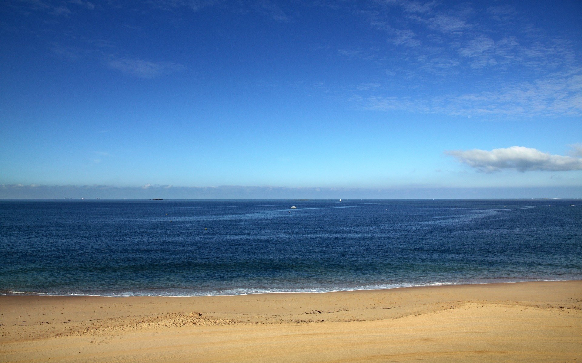 Sandy beach and blue ocean under a cloudy sky HD Wallpaper