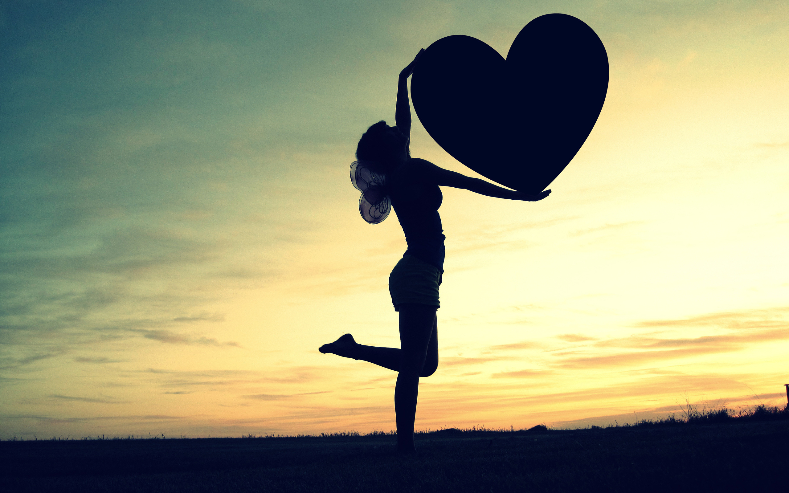 Silhouette of a girl holding a heart at sunset HD Wallpaper
