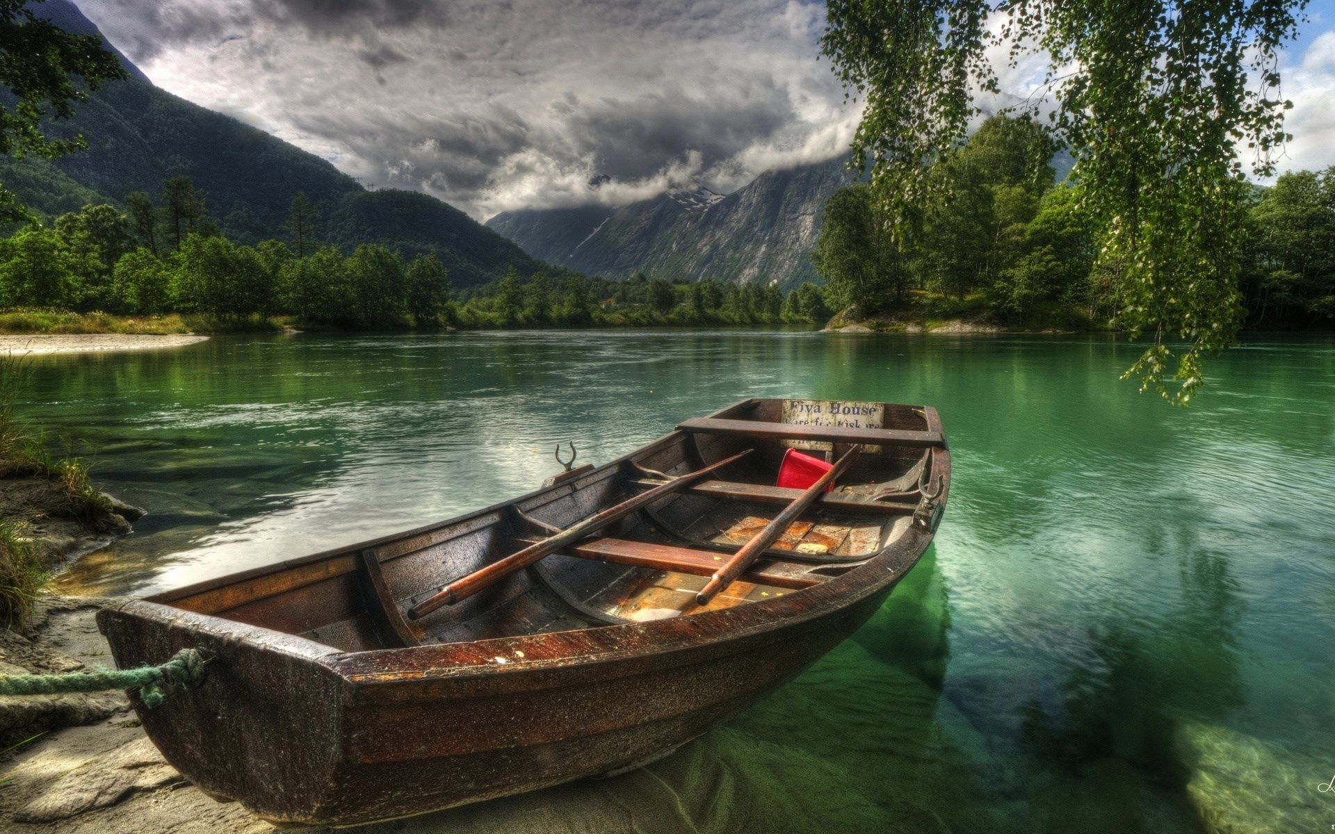 Wooden boat on a clear green river with mountains HD Wallpaper