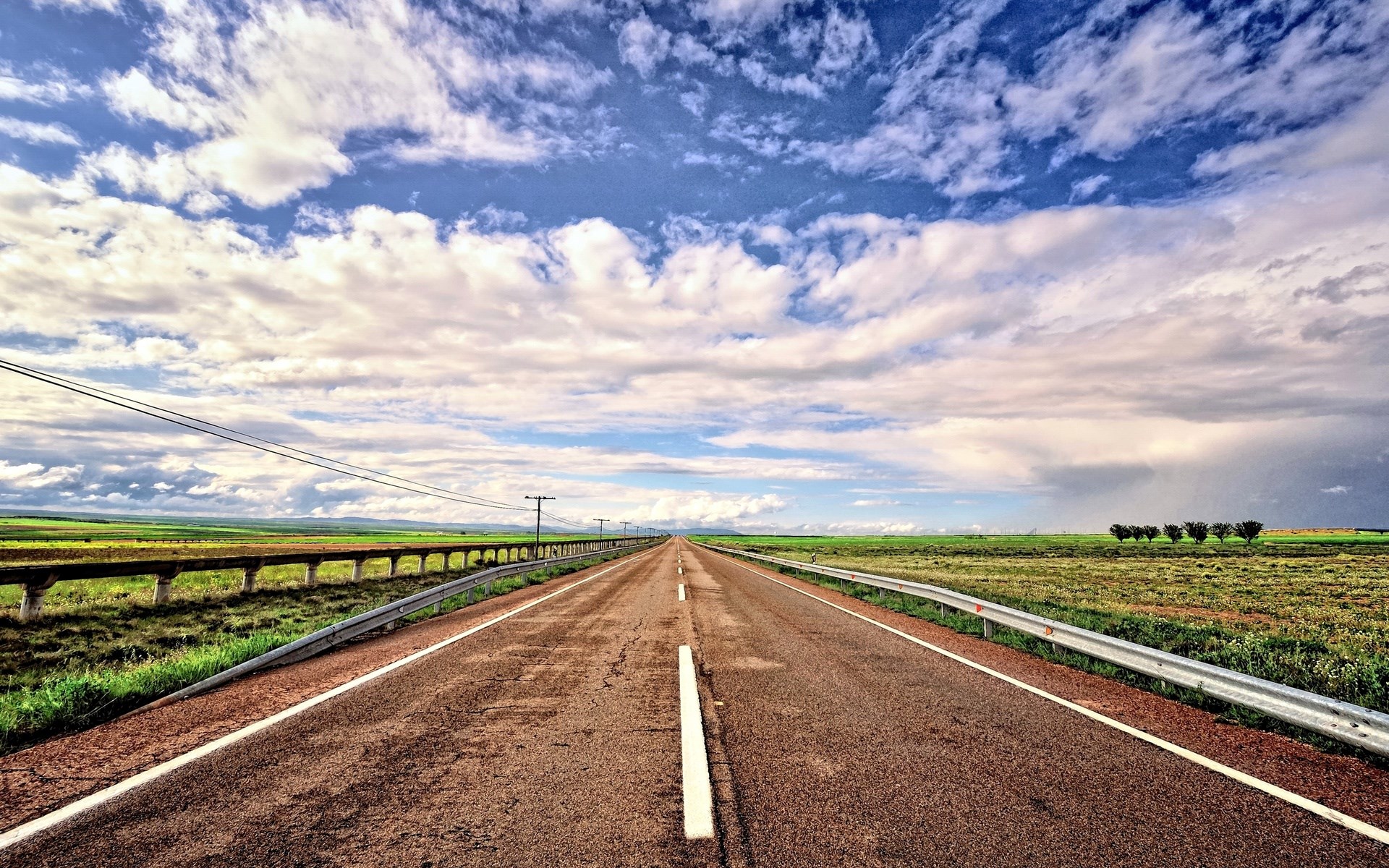 Empty highway stretching into the distance under a cloudy sky HD Wallpaper