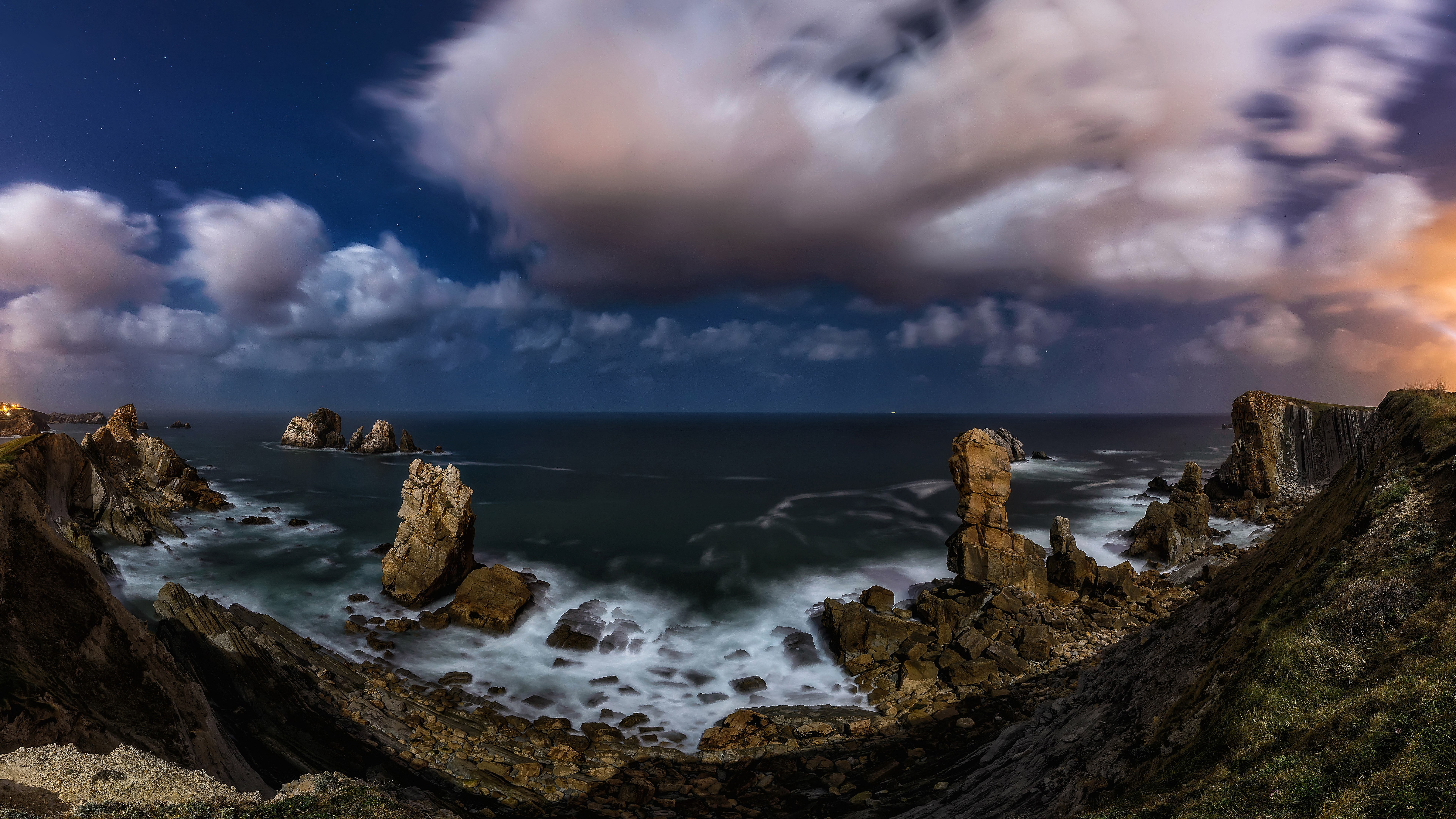 Rocky coastline at night with crashing waves and clouds HD Wallpaper