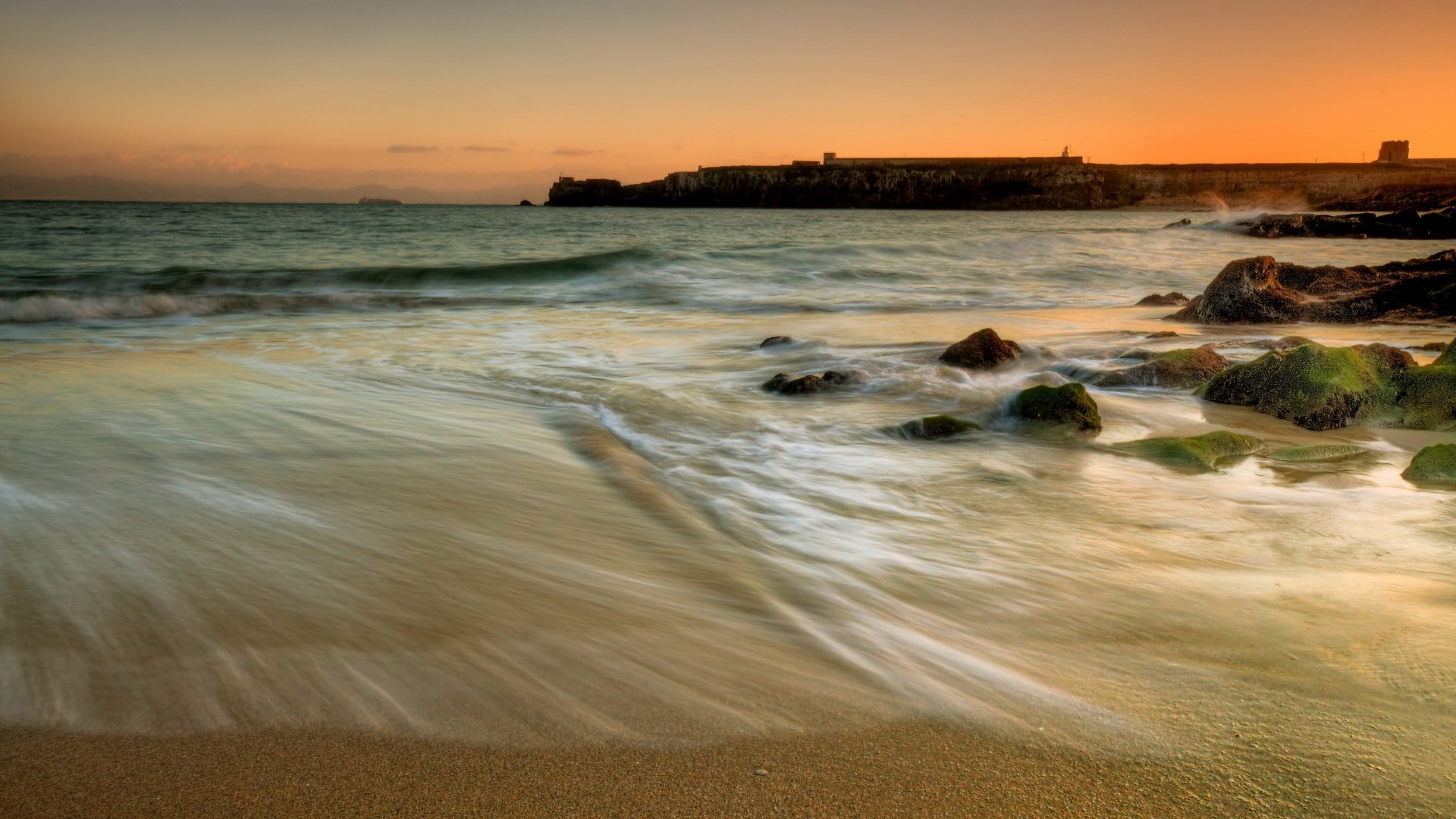 Beach with waves and rocks at sunset HD Wallpaper