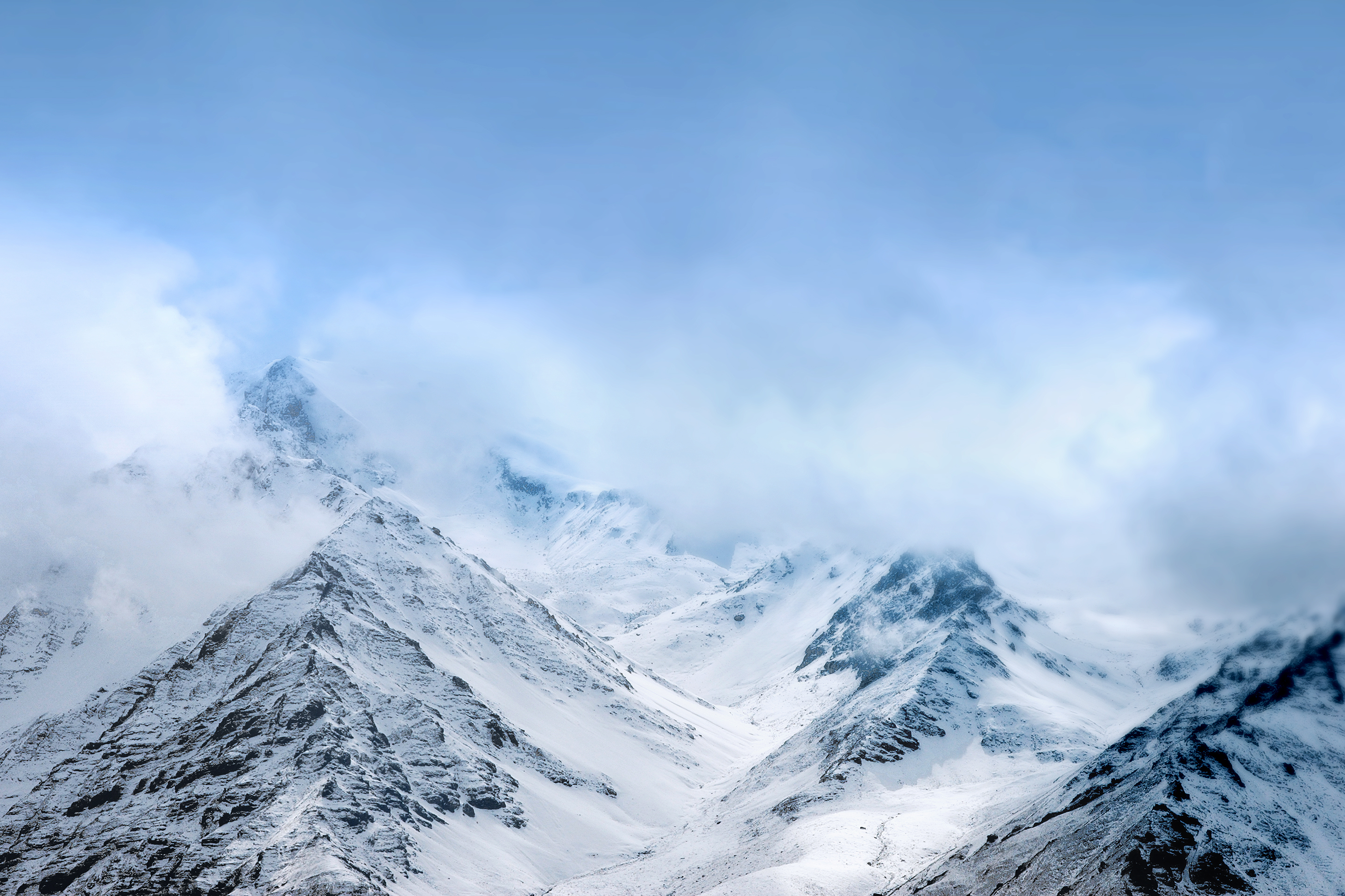 Snow-covered mountains under a cloudy sky HD Wallpaper