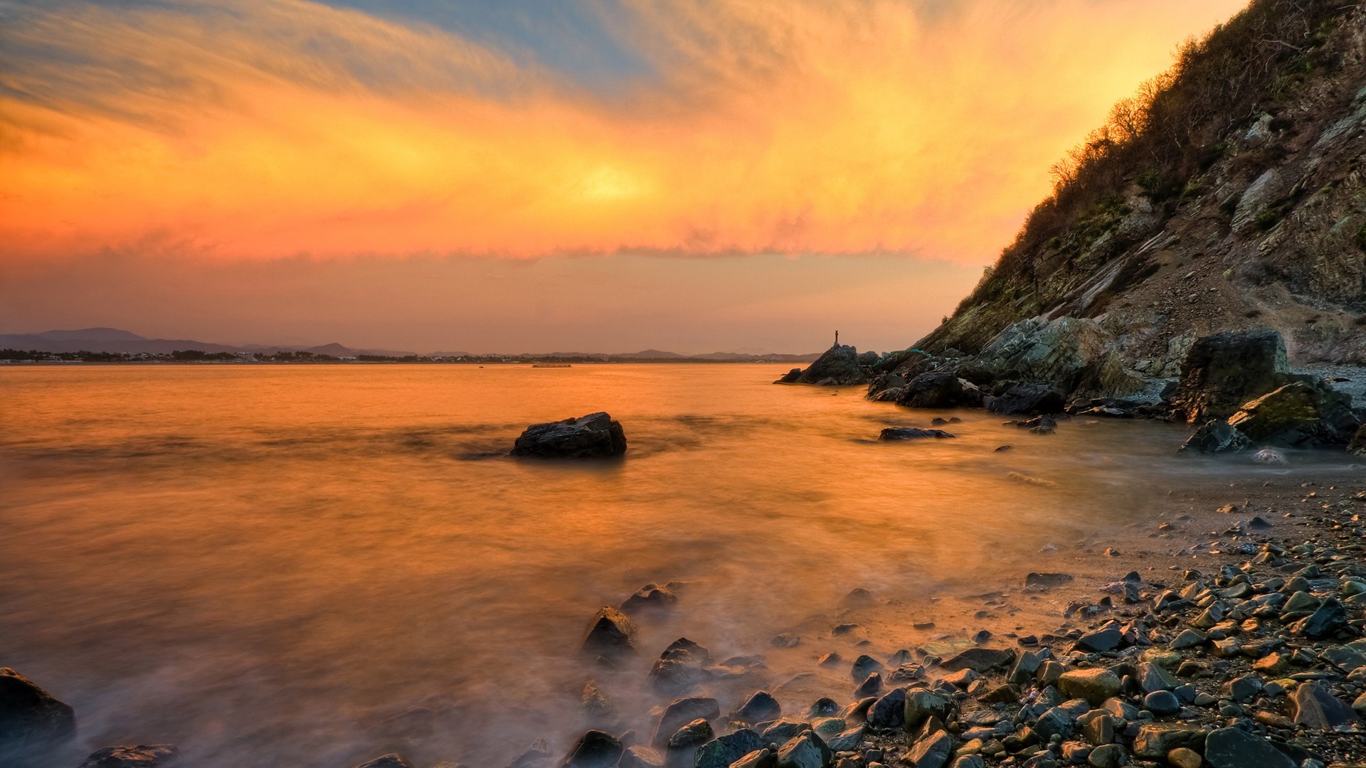 Sunset over a rocky coastline with calm water HD Wallpaper