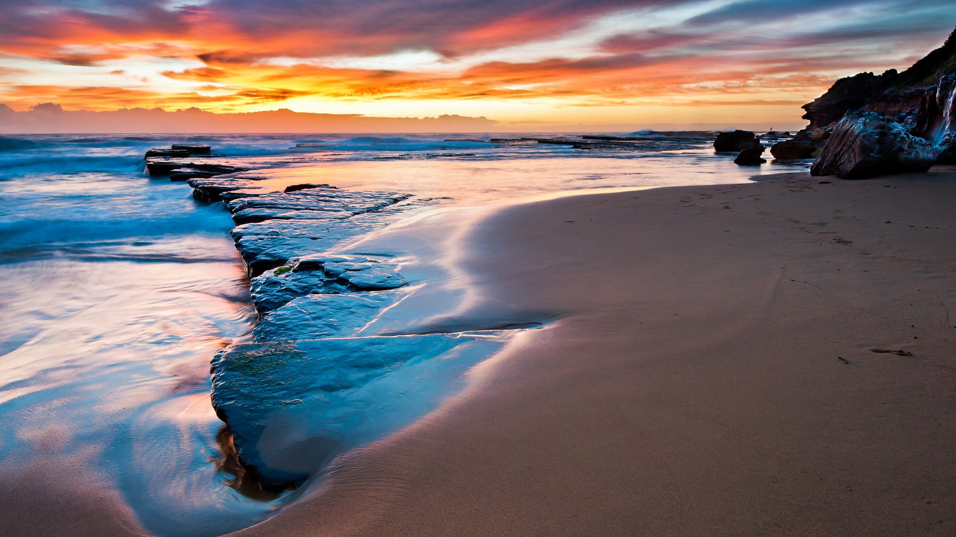 Sunset over a rocky beach with ocean waves HD Wallpaper