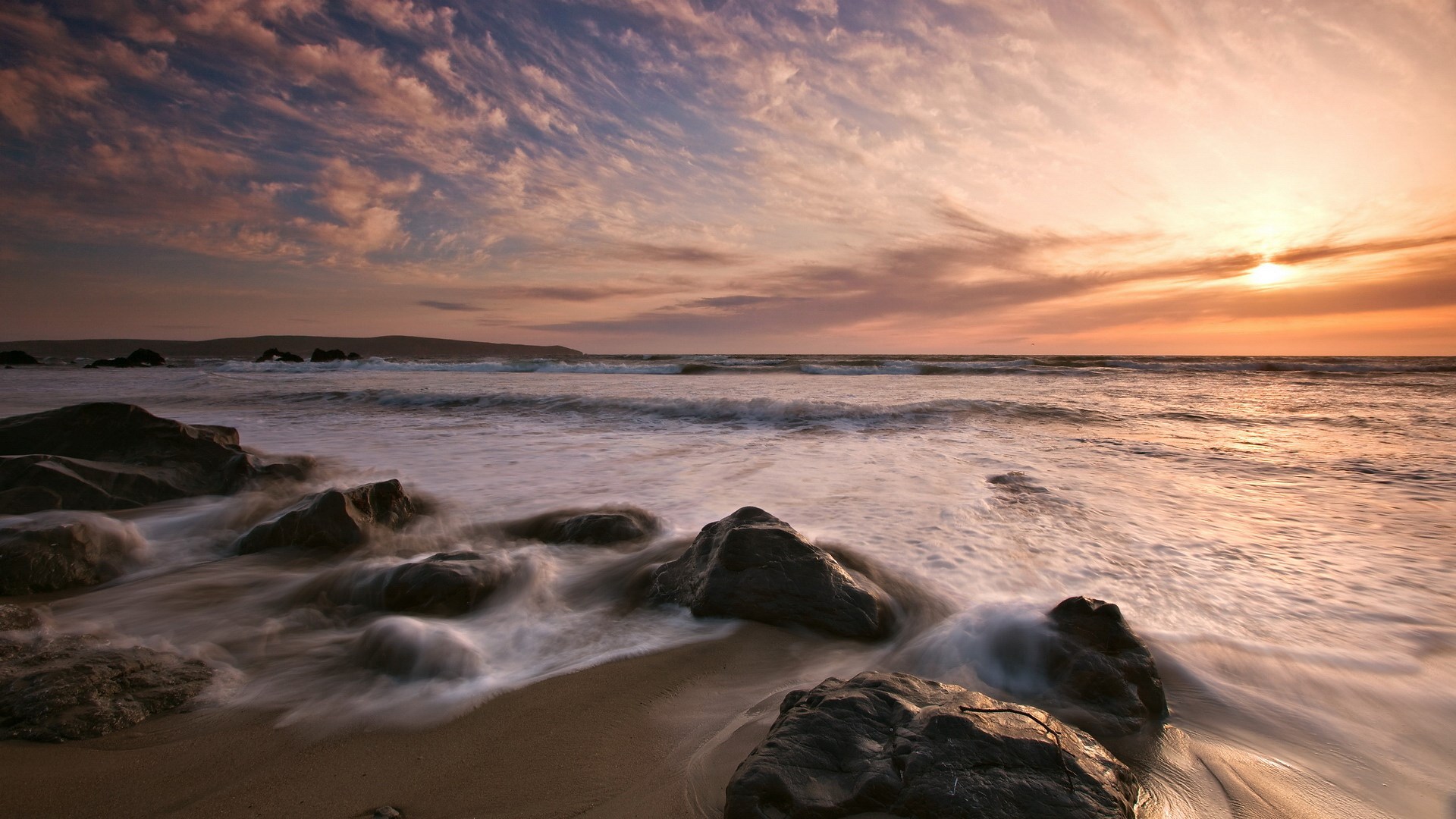 Sunset over a rocky beach with waves HD Wallpaper