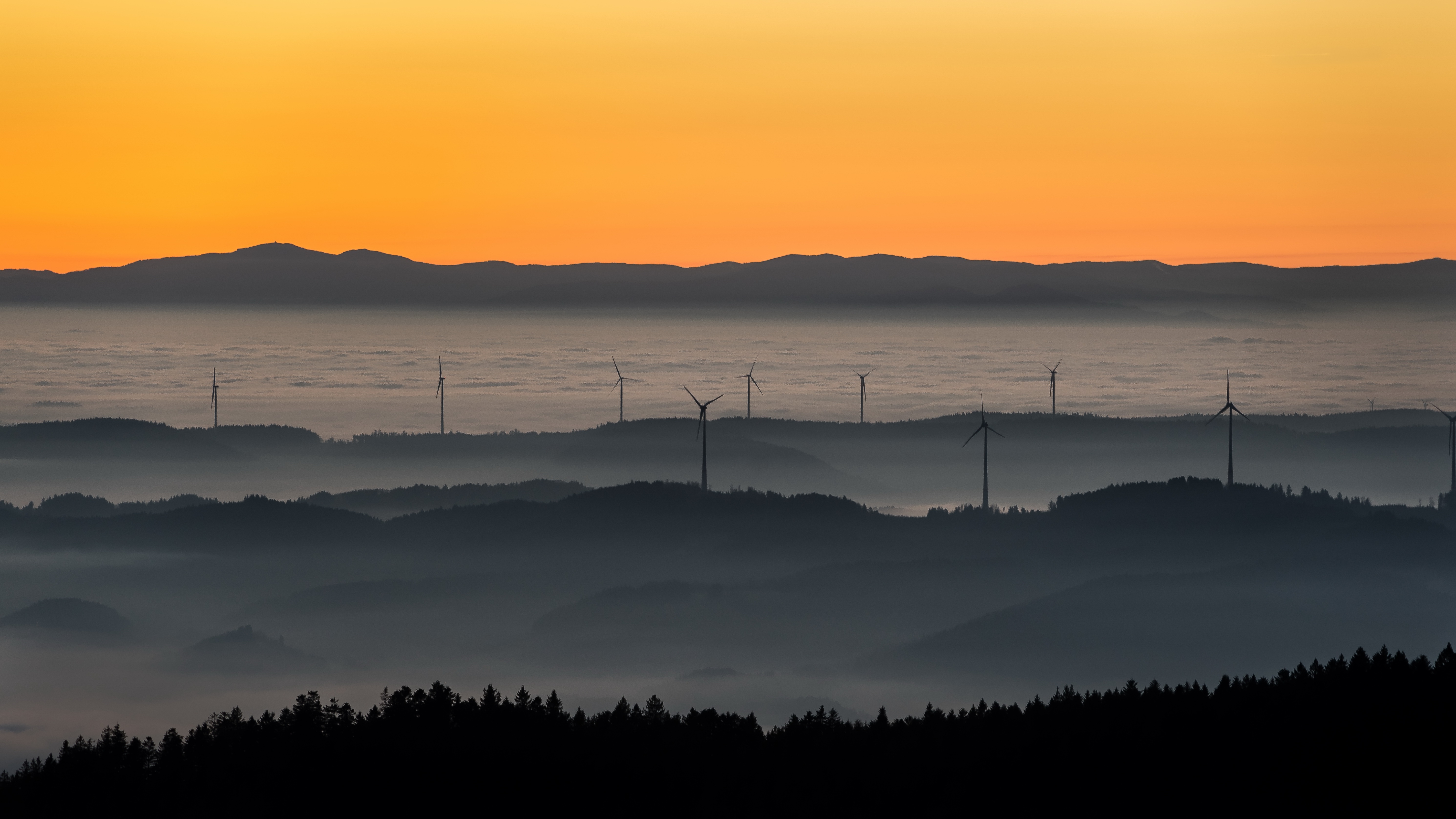 Wind turbines on misty hills at sunset HD Wallpaper