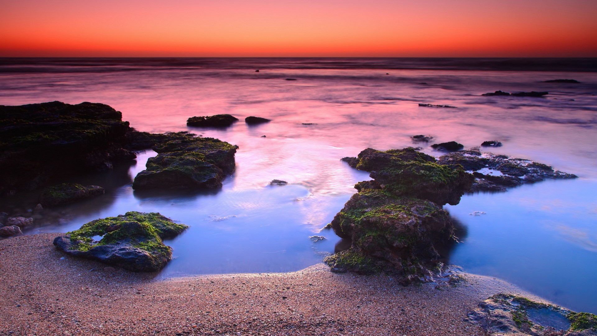 Sunset over rocky ocean shore with pink and orange sky HD Wallpaper