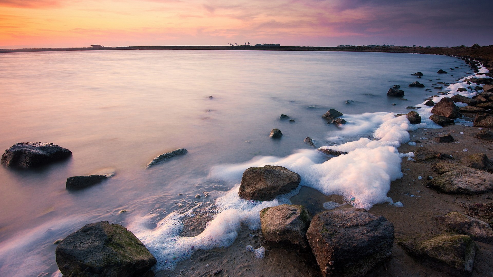 Calm water with rocks and foam at sunset HD Wallpaper