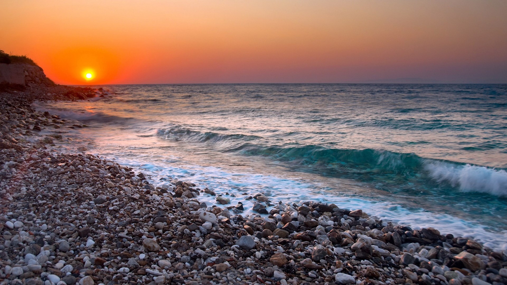 Sunset over a rocky beach and ocean waves HD Wallpaper