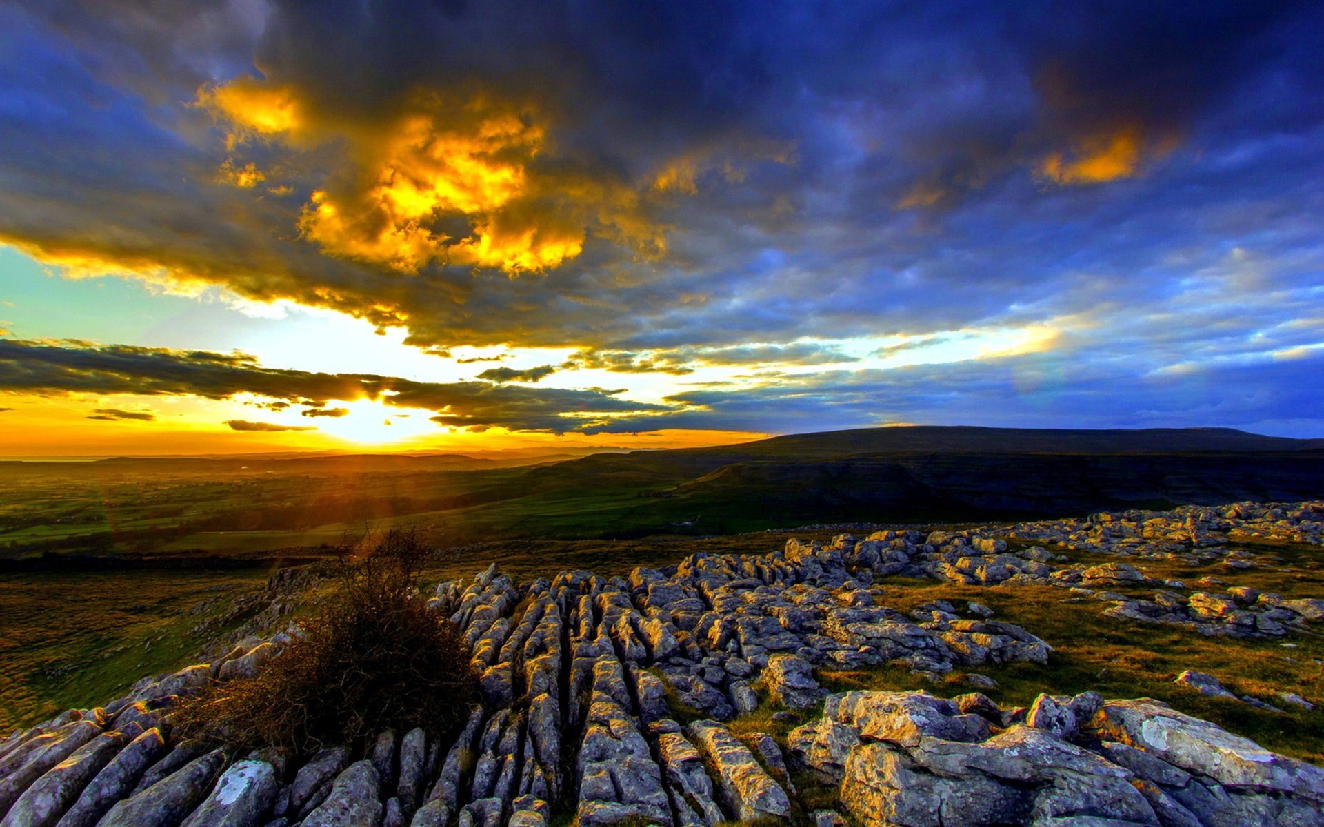 Sunset over rocky landscape with dramatic clouds HD Wallpaper