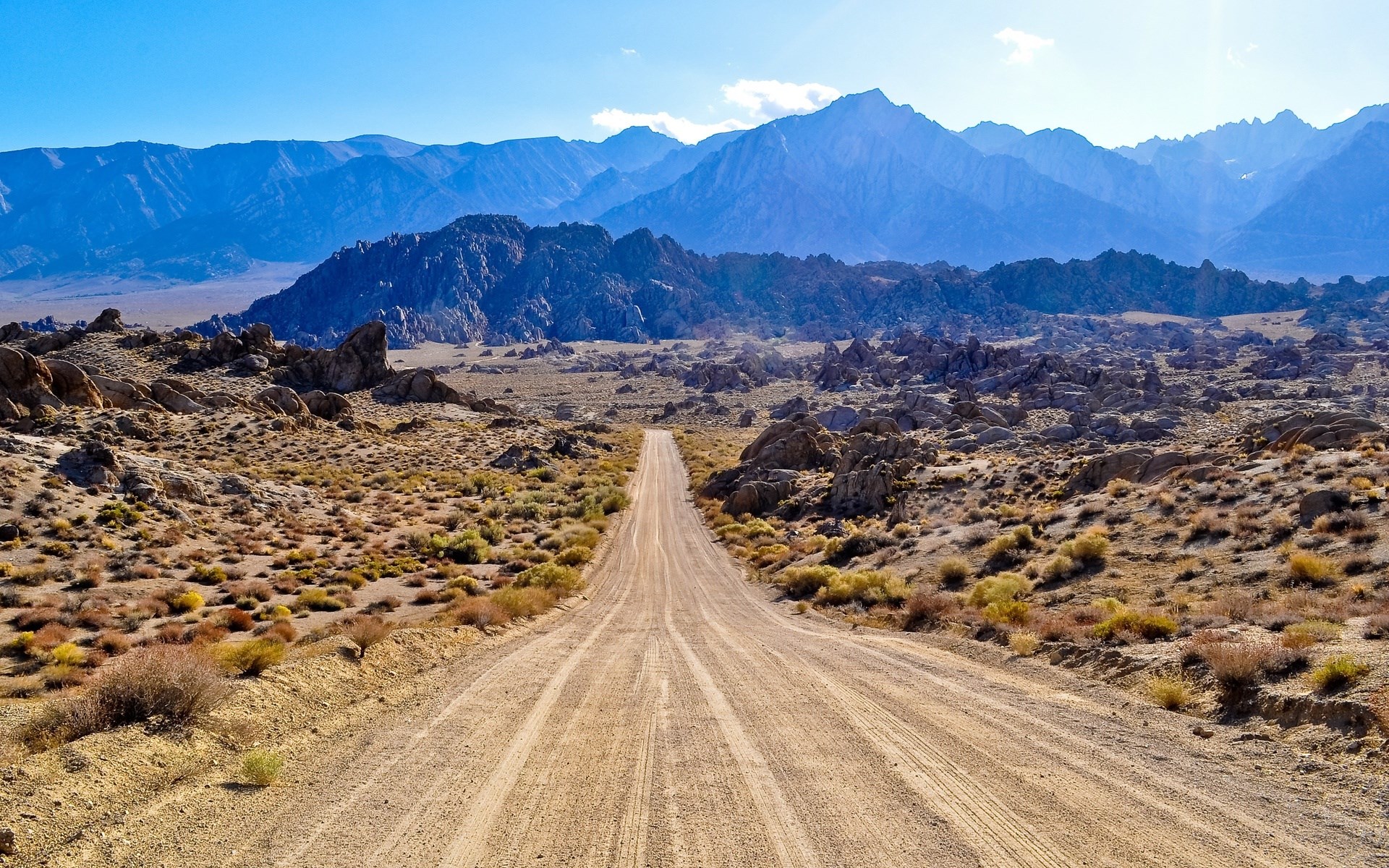 Dirt road leading to mountains in a desert landscape HD Wallpaper