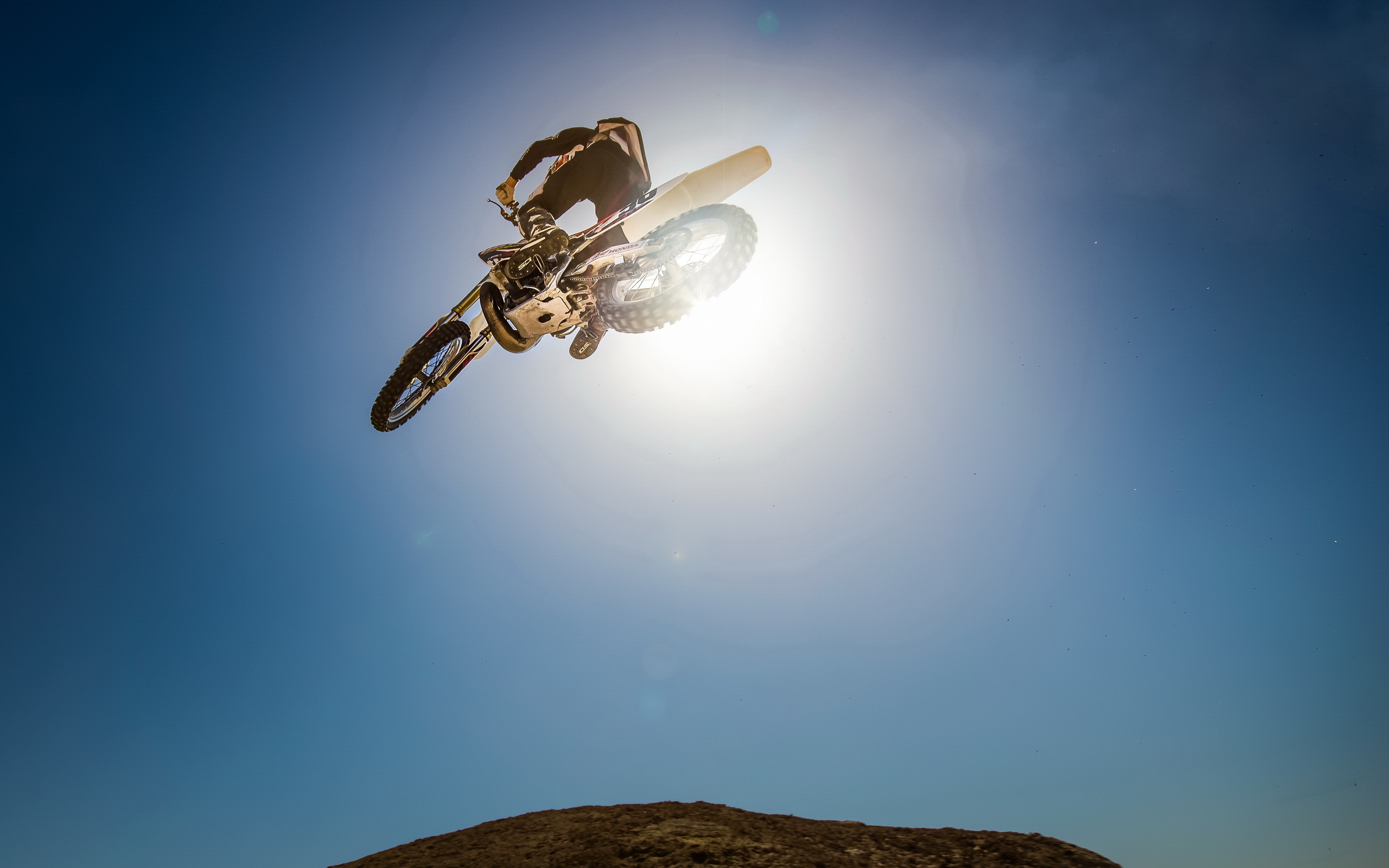 Motocross rider performing a jump against the sun HD Wallpaper