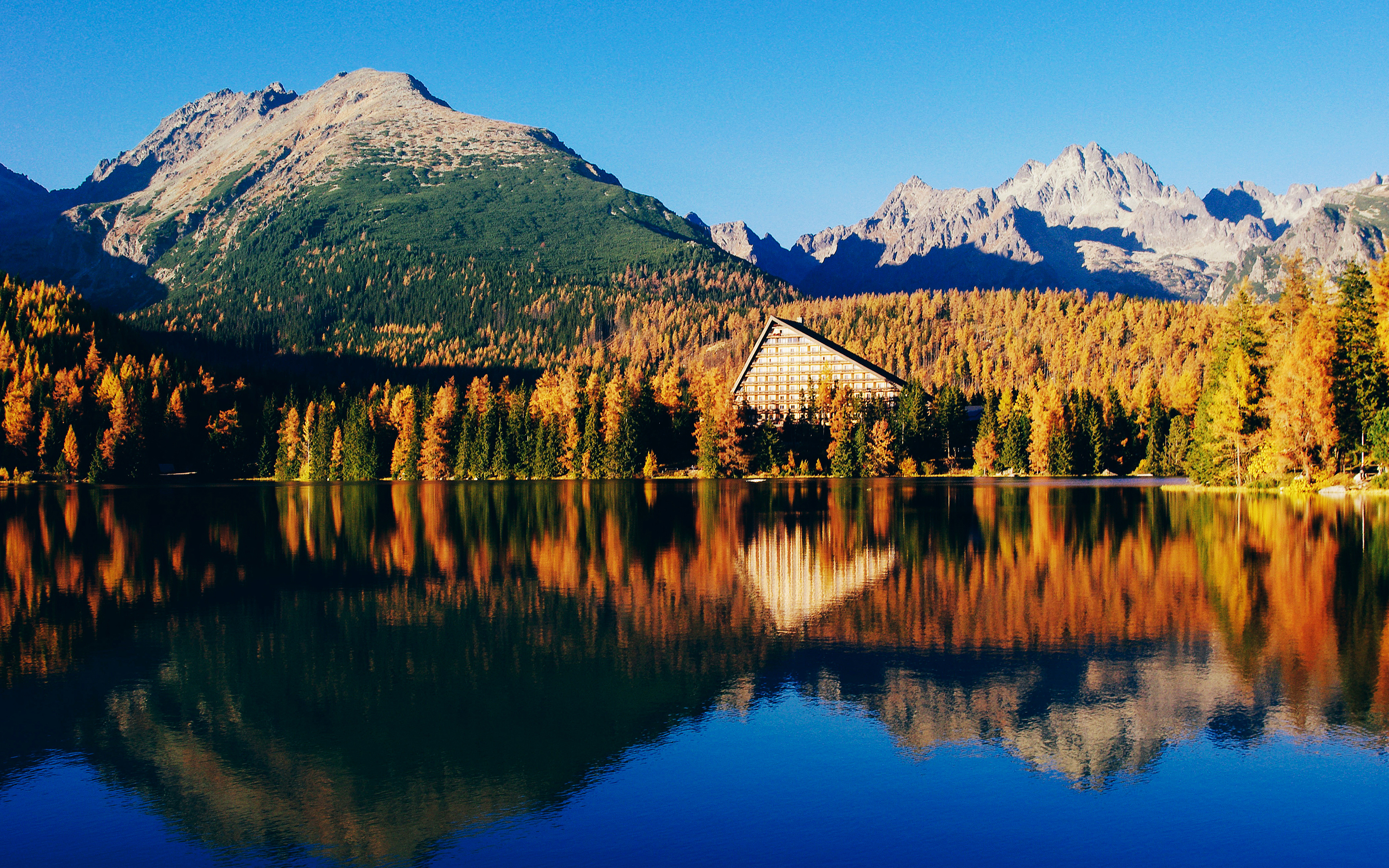 Mountain lake with autumn trees and hotel HD Wallpaper