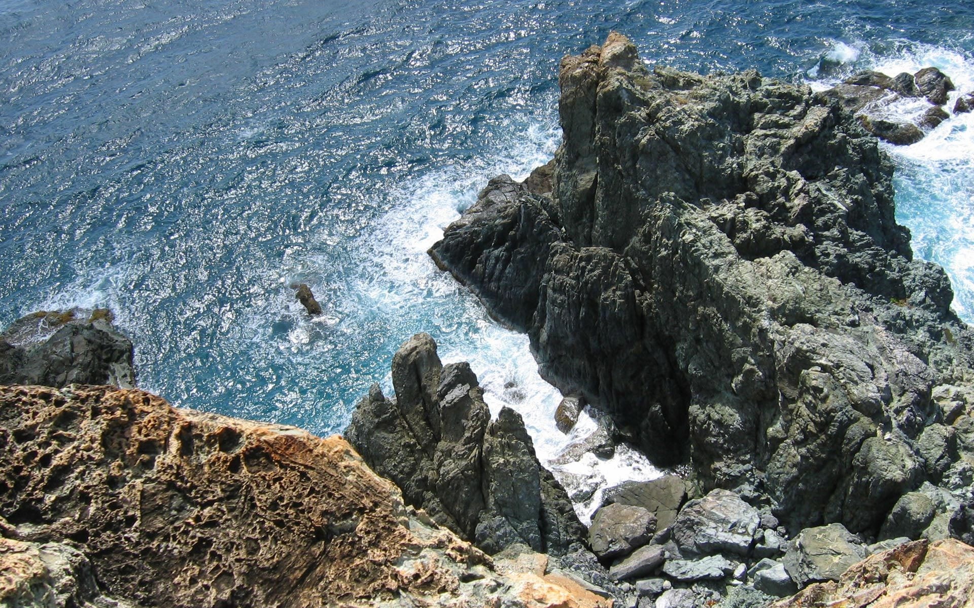 Rocky coastline with waves crashing against rocks HD Wallpaper