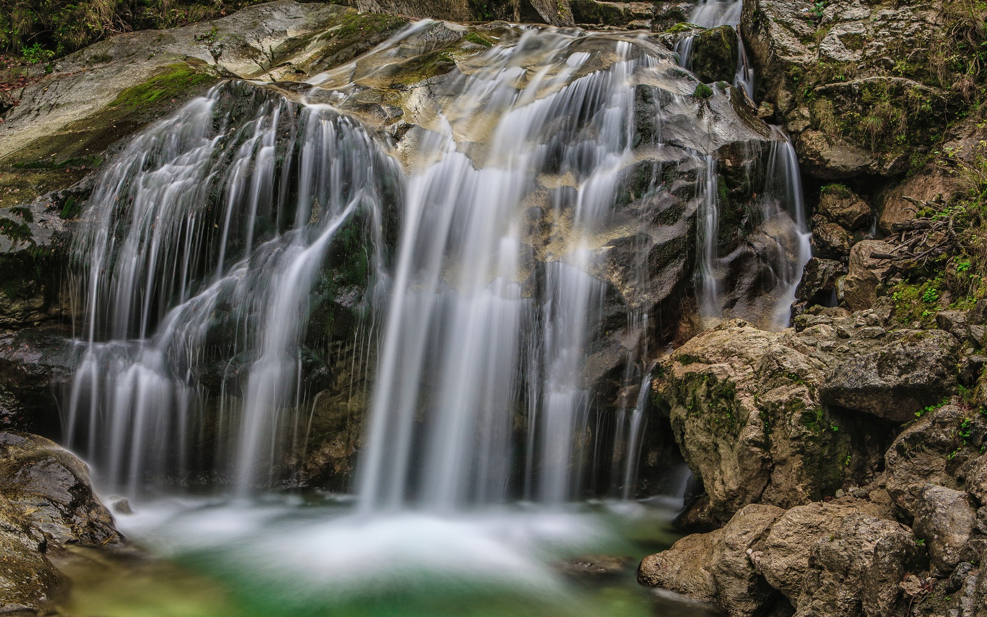 Waterfall cascading over mossy rocks into a pool HD Wallpaper