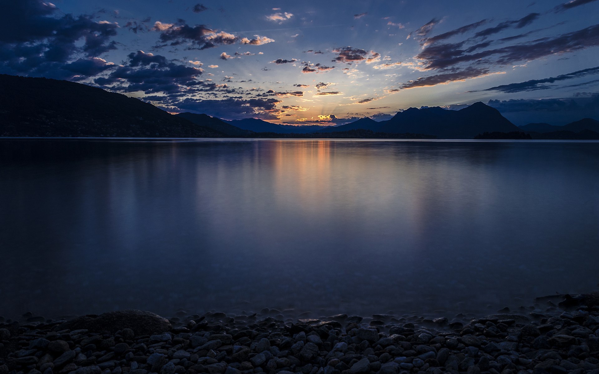 Sunset over a calm lake with mountains and clouds HD Wallpaper