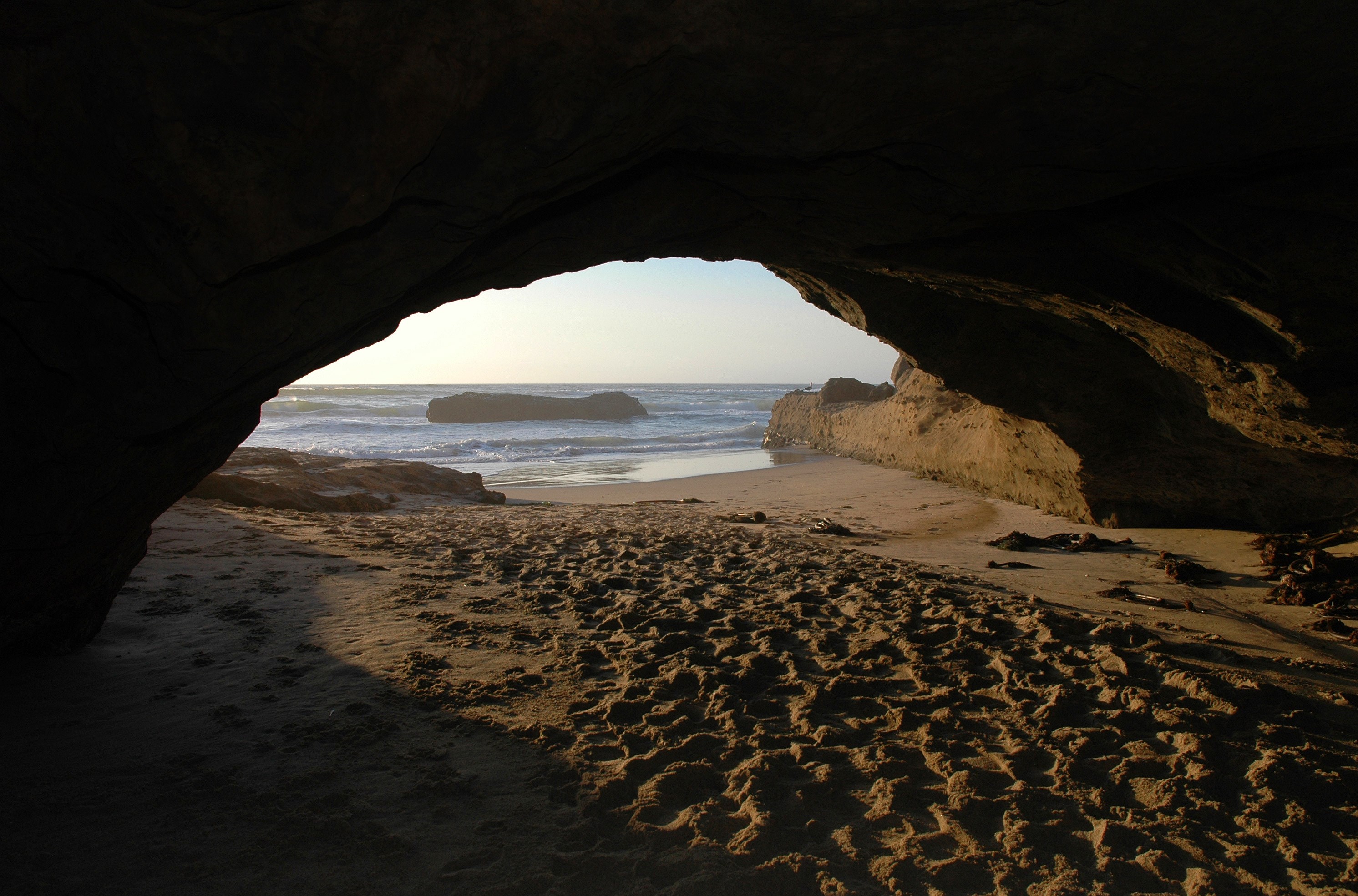 Cave entrance overlooking a beach and ocean HD Wallpaper