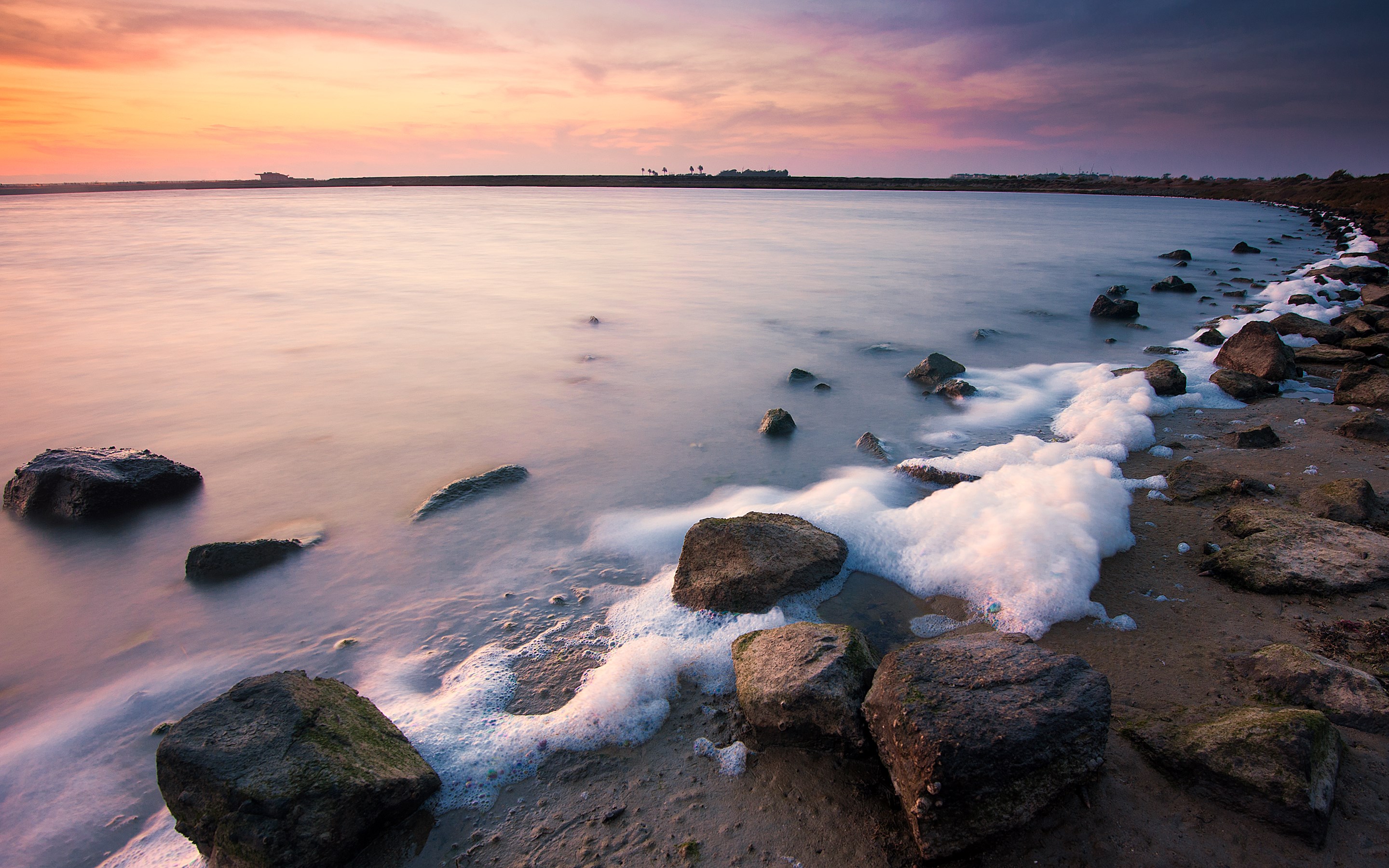 Ocean waves with foam washing over rocks at sunset HD Wallpaper