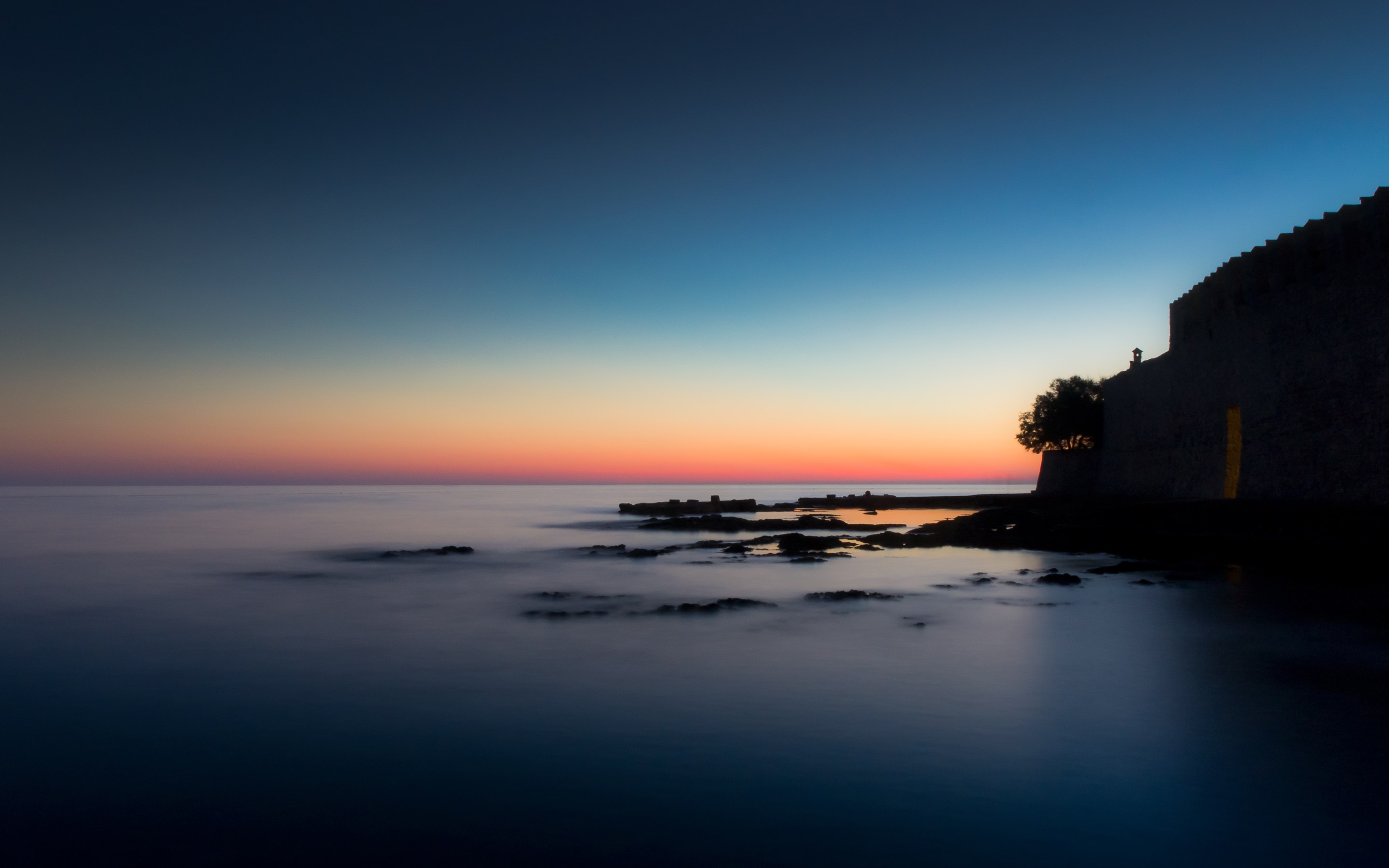 Sunset over the sea with a stone wall and tree HD Wallpaper