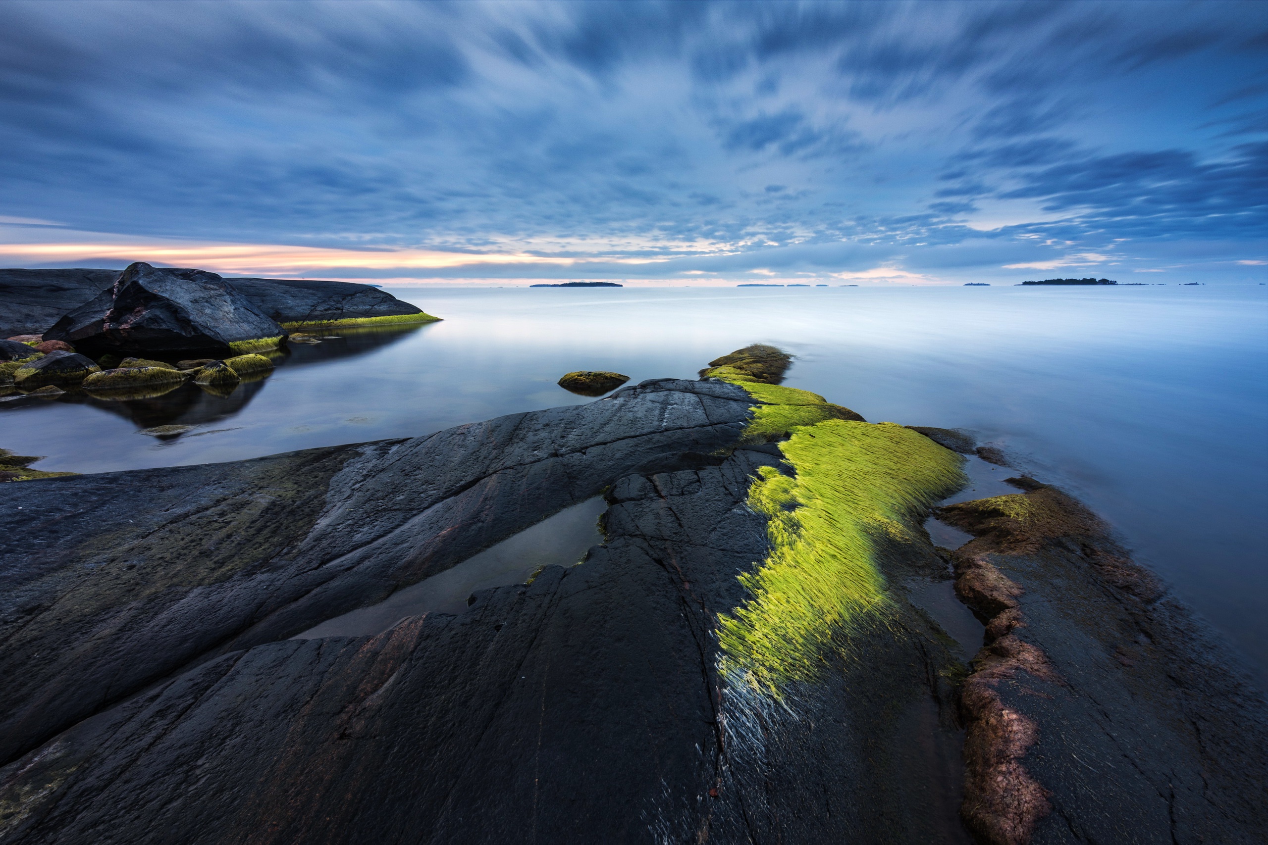 Rocky coastline with calm ocean and cloudy sky HD Wallpaper