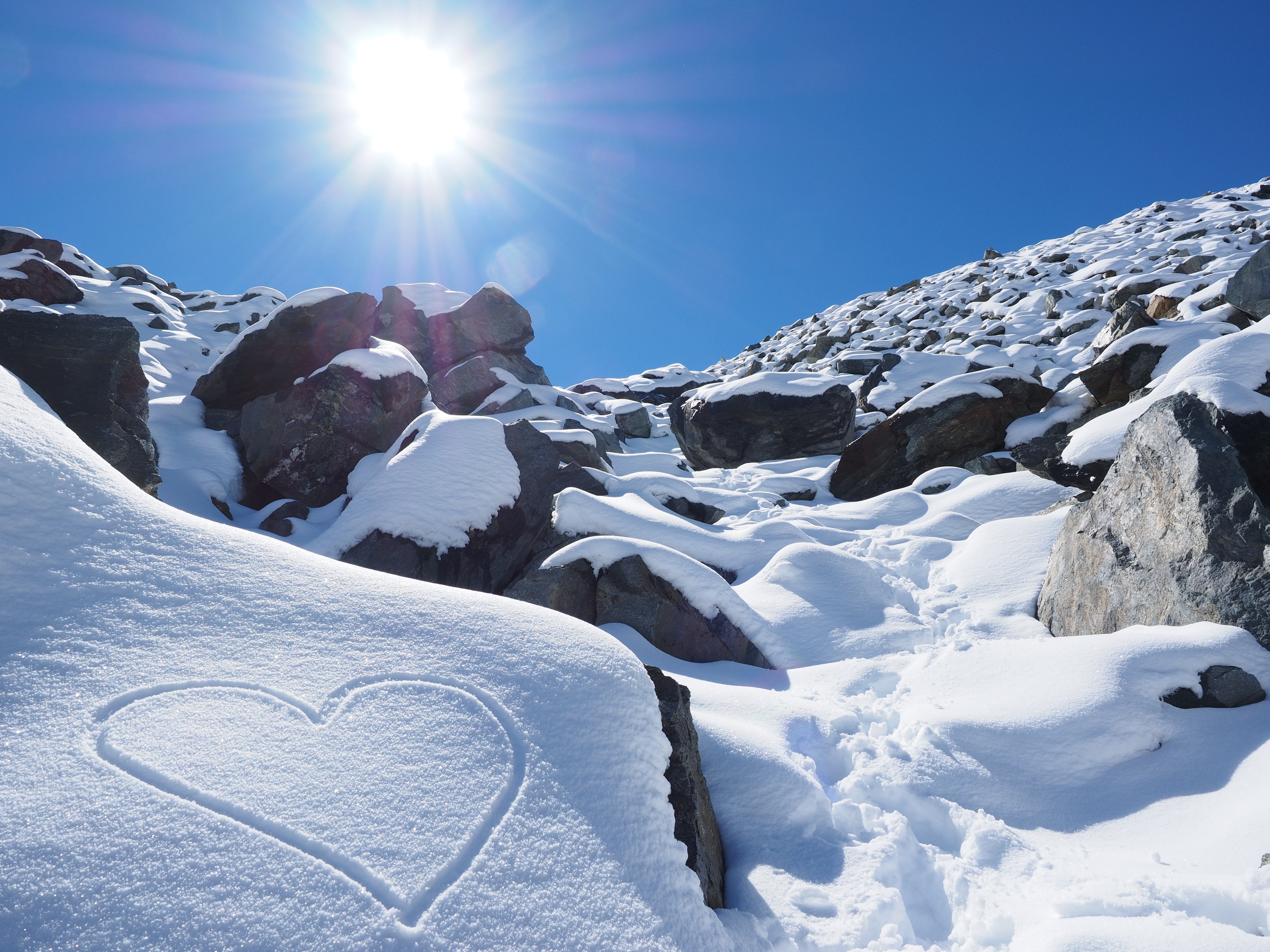 Heart drawn in snow on a rocky mountain slope HD Wallpaper
