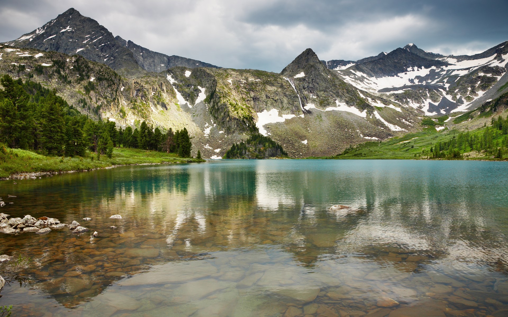 Turquoise mountain lake with rocky shore and snow-capped peaks HD Wallpaper