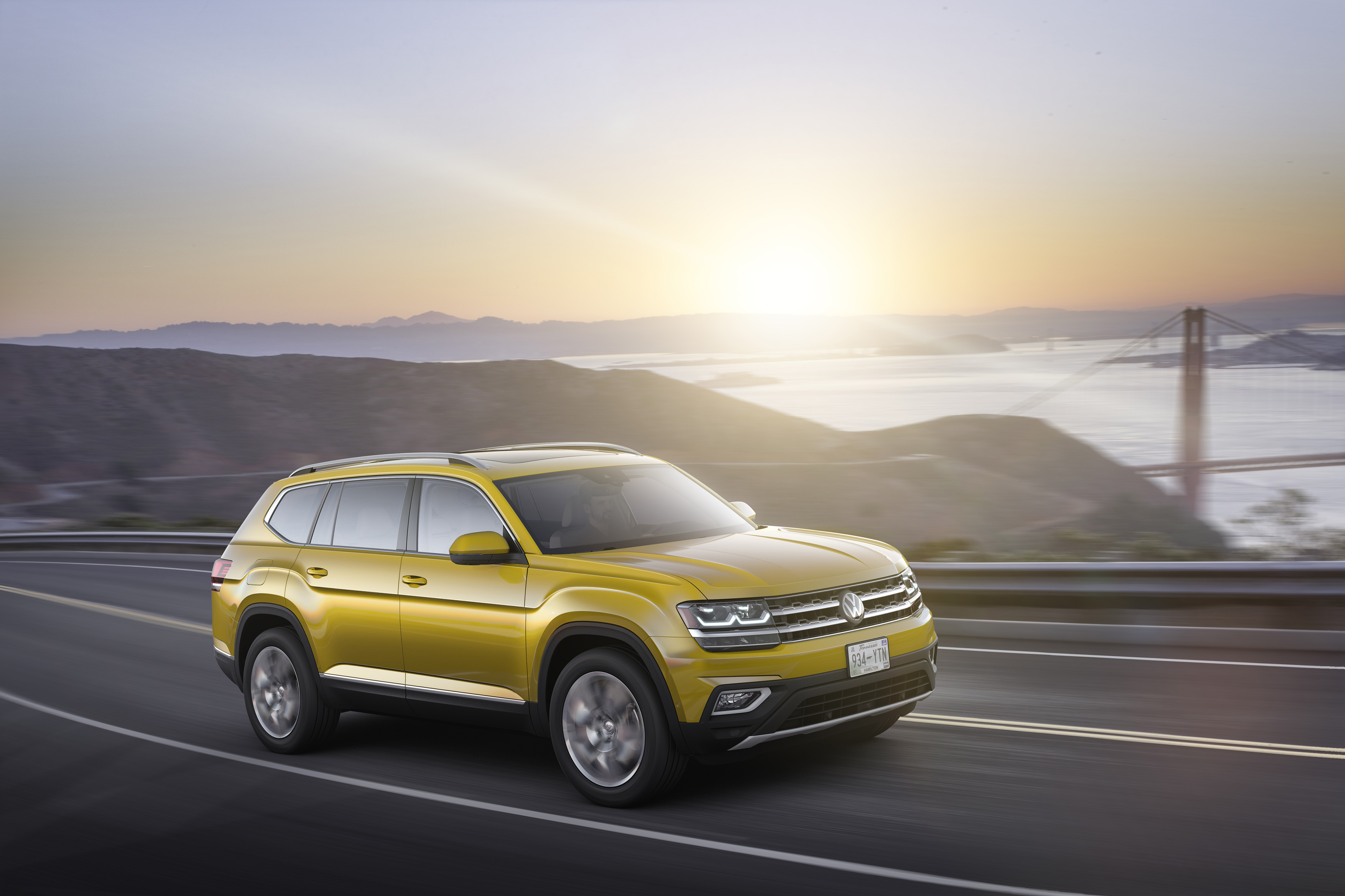 Yellow Volkswagen Atlas SUV driving near Golden Gate Bridge HD Wallpaper