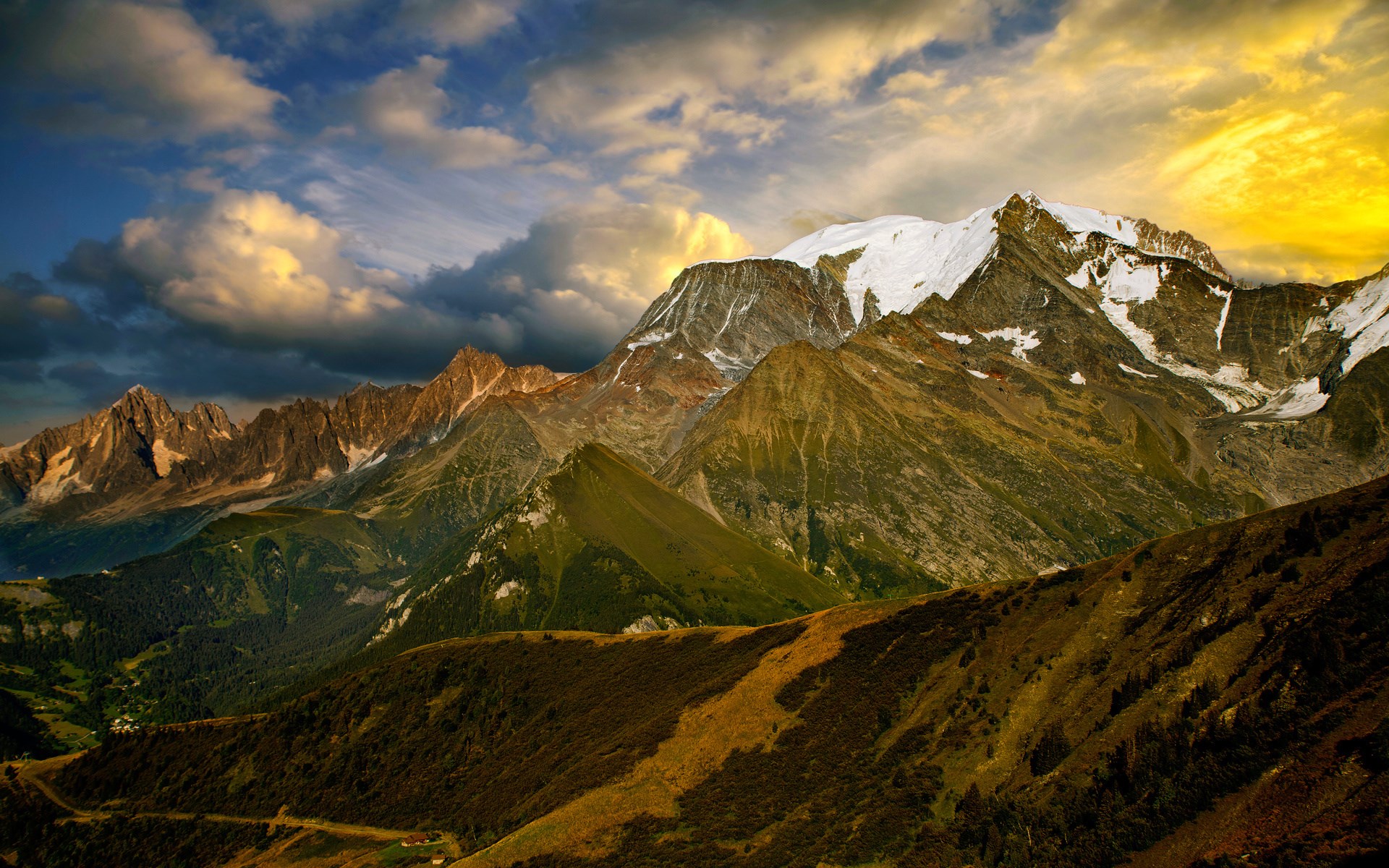 Majestic mountain range with snow-capped peaks under a dramatic sky HD Wallpaper